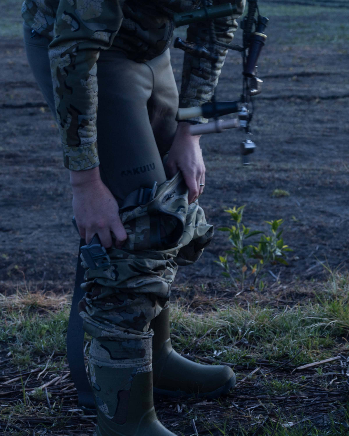Hunter wearing StrongFleece 290 Layering Pant in Ash Brown underneath KUIU HD Flex Wader, side facing view