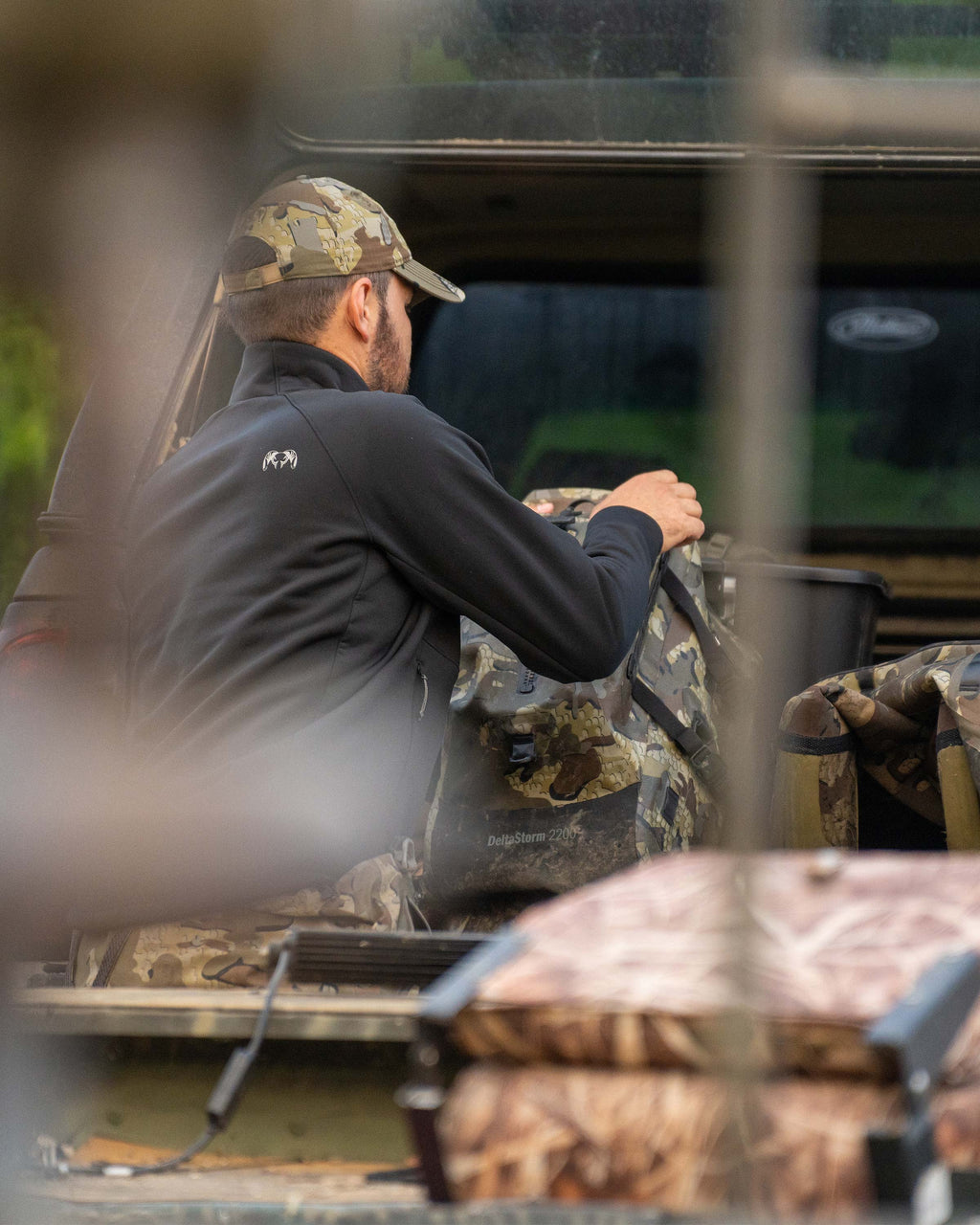 Hunter Loading Pack into Truck Bed Wearing StrongFleece 290 WF Full Zip in Black Highlighting  Raised Collar