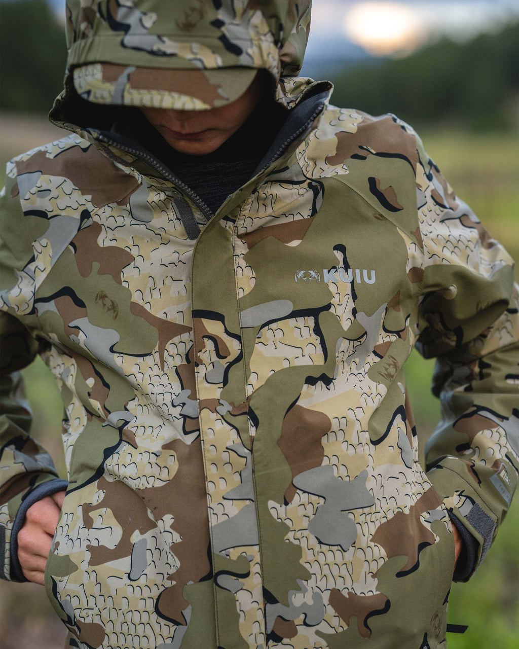 Close-up of a young male teenager wearing Youth Versa Jacket in Valo camouflage, slipping his hands into his pockets.