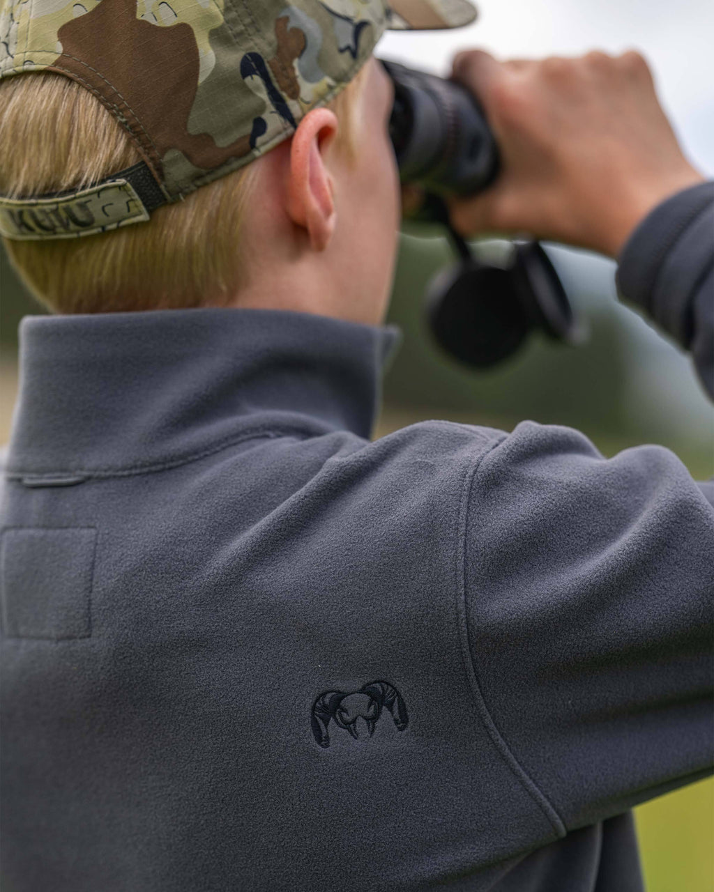 Close-up right shoulder view of embroidered ram on a Youth Versa Fleece Full Zip in Gunmetal Grey.