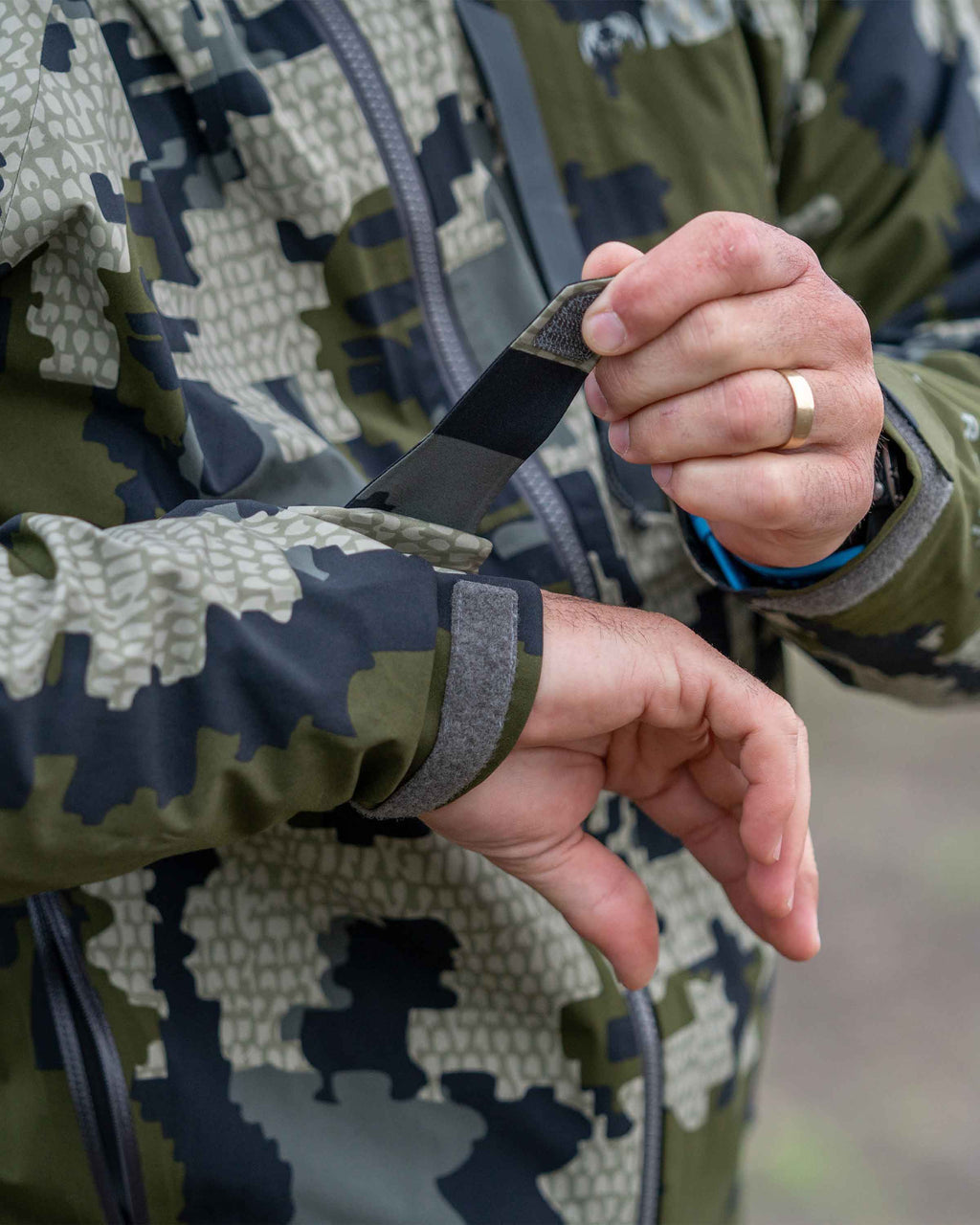Hunter adjusting cuff on Chugach TR Rain Jacket in Verde Camouflage