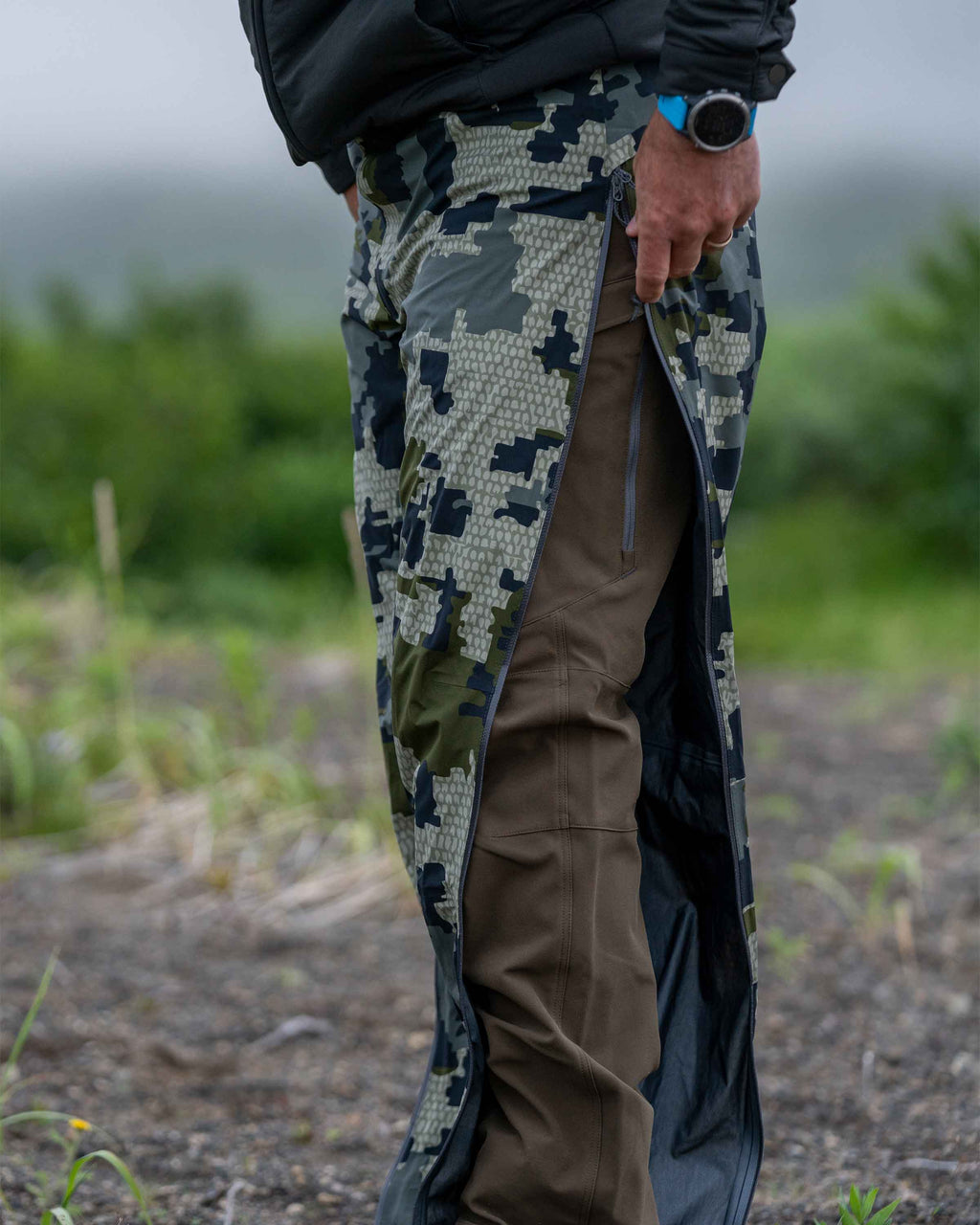 Hunter Wearing Chugach TR Rain Pant in Verde Camouflage with Unzipped, Full Length YKK Aquaguard Leg Zippers
