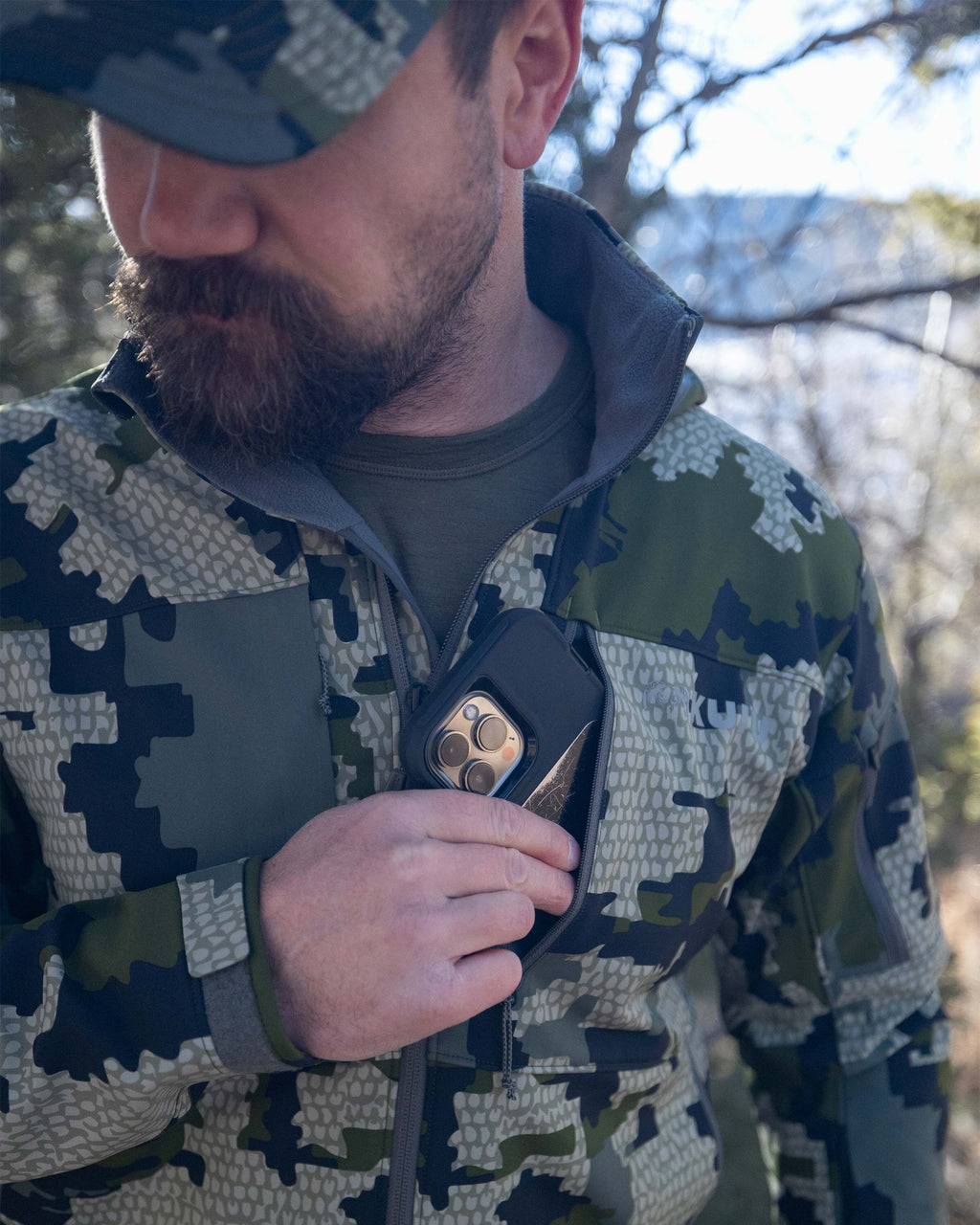 Hunter Removing Phone From YKK Zippered Chest Pocket on Guide PRO Hooded Jacket in Verde Camouflage