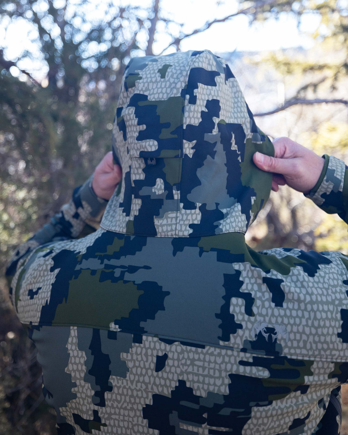 Hunter in Guide PRO Hooded Jacket in Verde Camouflage with Both Hands on 2-way Adjustable Storm Hood