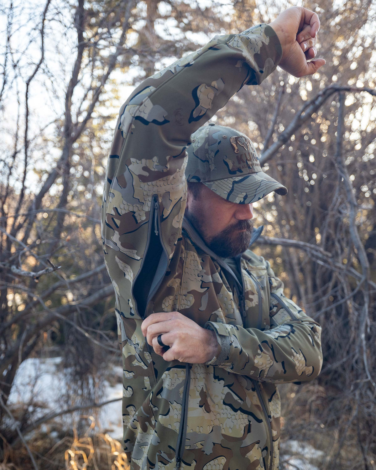 Hunter Standing in Wooded Area Opening YKK Pit Zippers on Guide PRO Hooded Jacket in Valo Camouflage