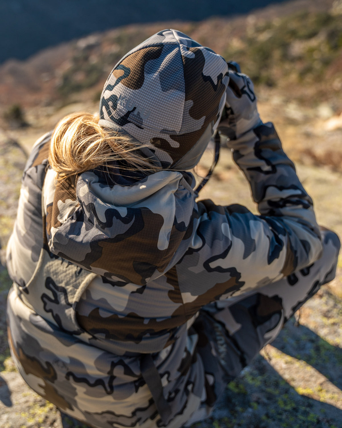 Top back view of female hunter wearing Women's Kenai Hooded Jacket in Vias Camouflage glassing