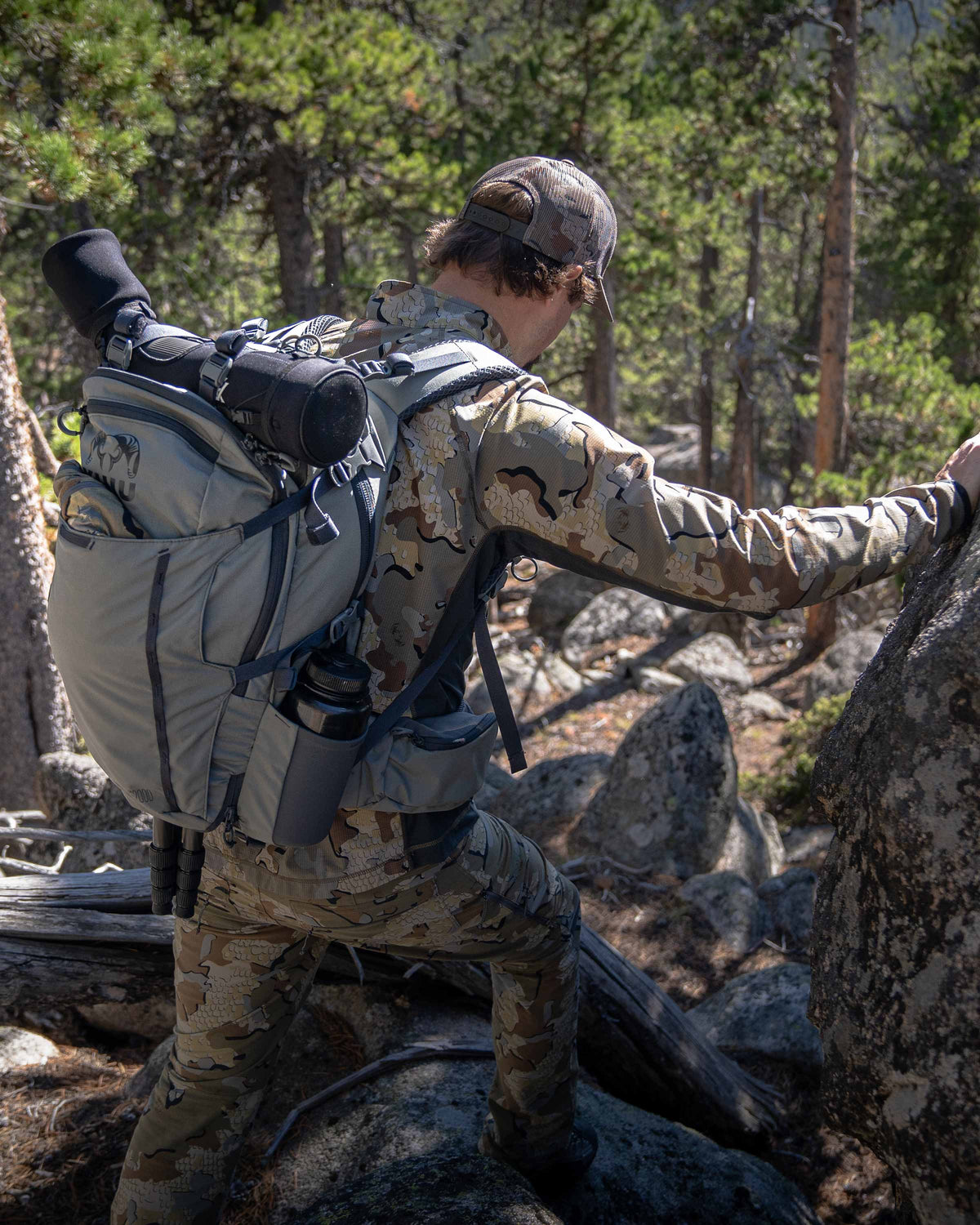 Hunter wearing Valo Camouflage and Venture Divide 2000 in Stone with a spotting scope in the divide pouch walking away from camera