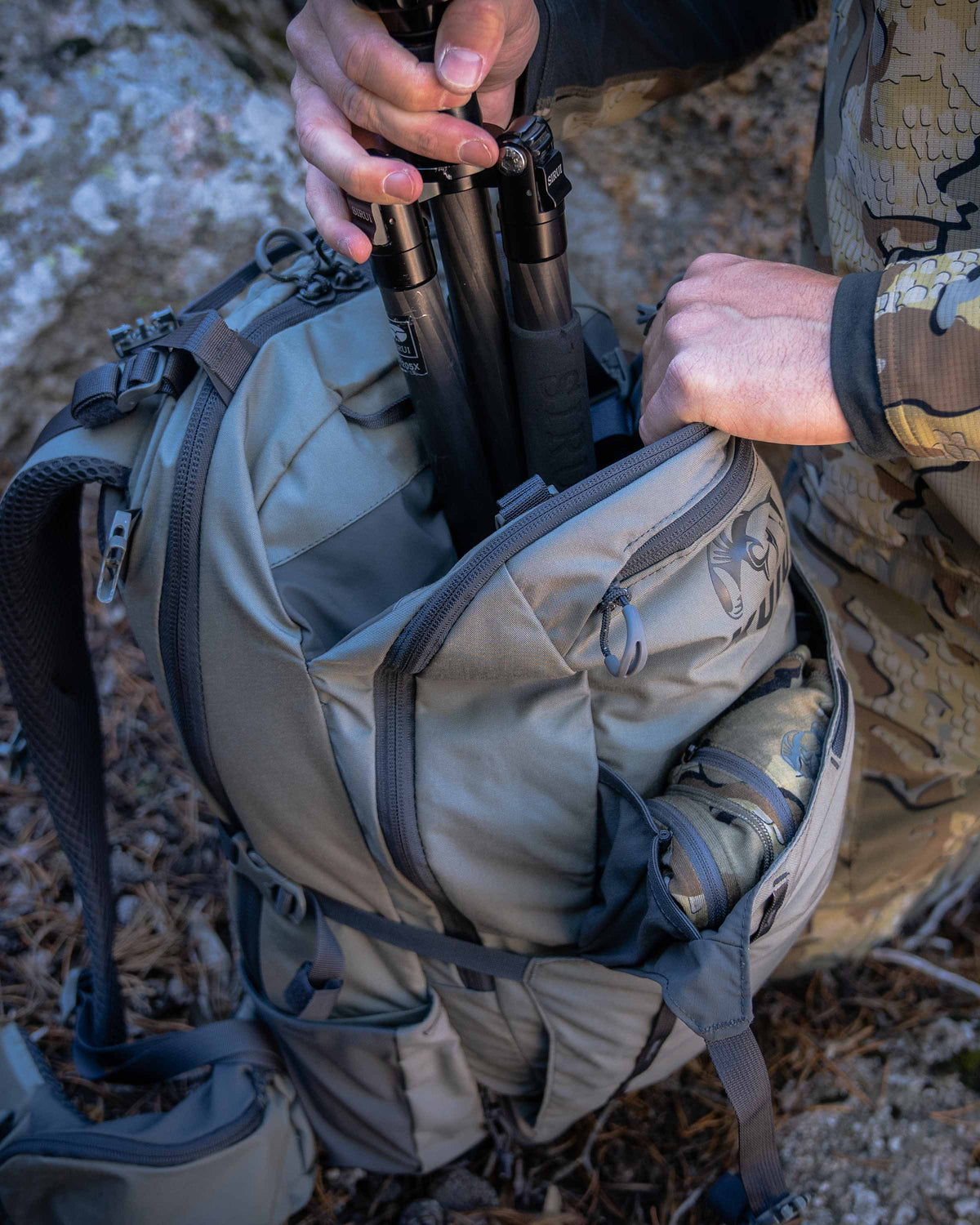 Hunter sliding a spotting scope into the Divide pouch of the Venture Divide 2000 in Stone