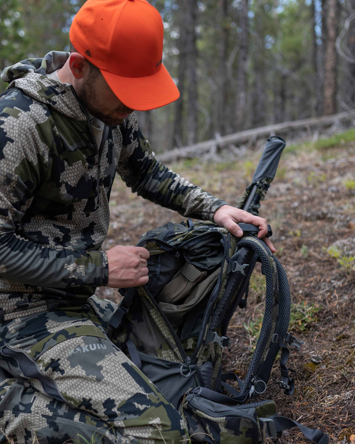Hunter kneeling and accessing gear from the side of the Venture Divide 3000 Pack in Verde Camouflage