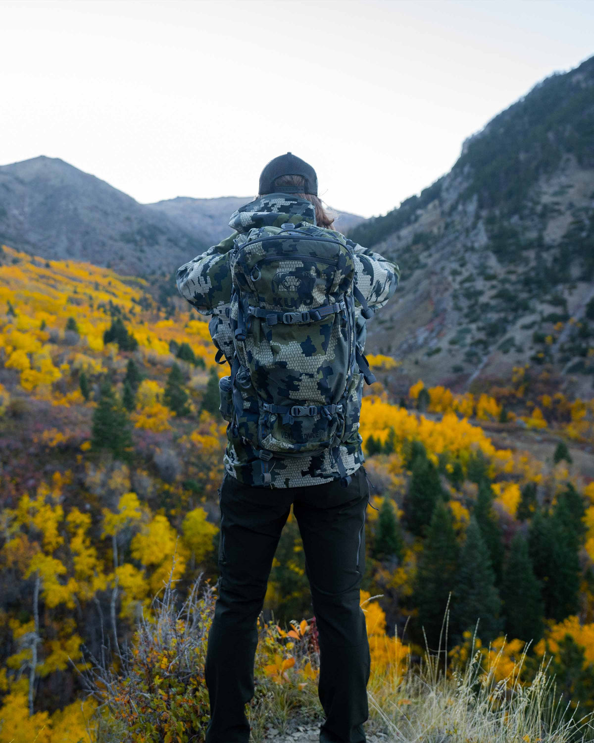 Hunter wearing the Venture Divide 3000 Pack in Verde Camouflage using binoculars facing away from camera