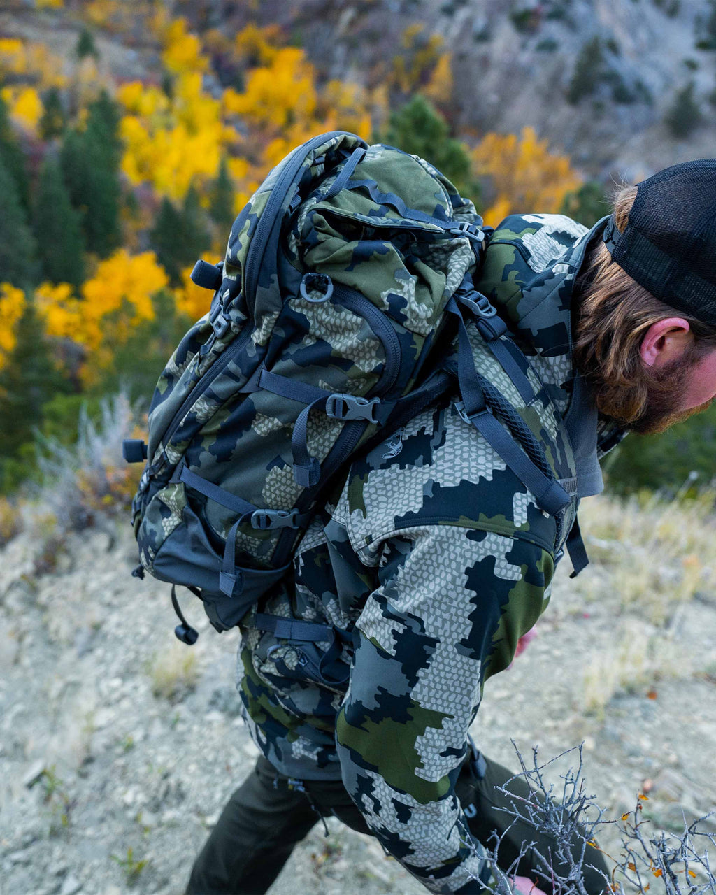 Hunter wearing the Venture Divide 3000 Pack in Verde Camouflage hiking up and out of the frame