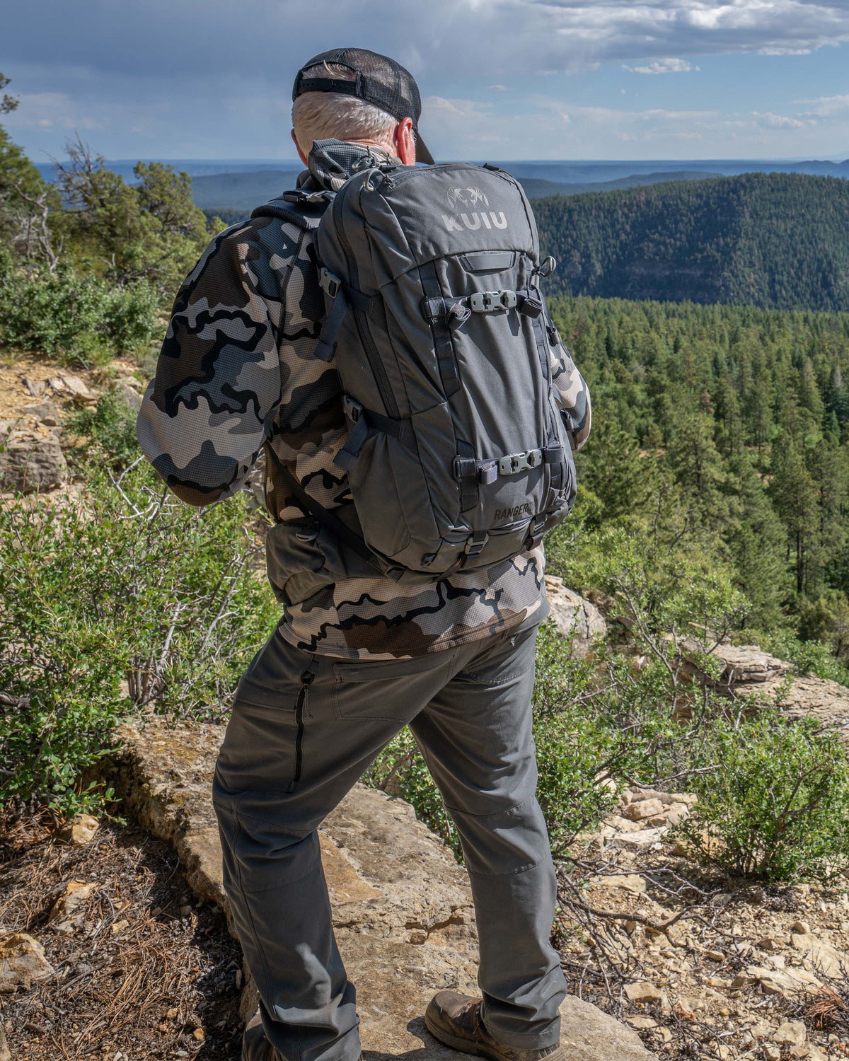 Hunter gazing down on an edge of a rocky cliff carrying Ranger 2200 in Gunmetal Grey