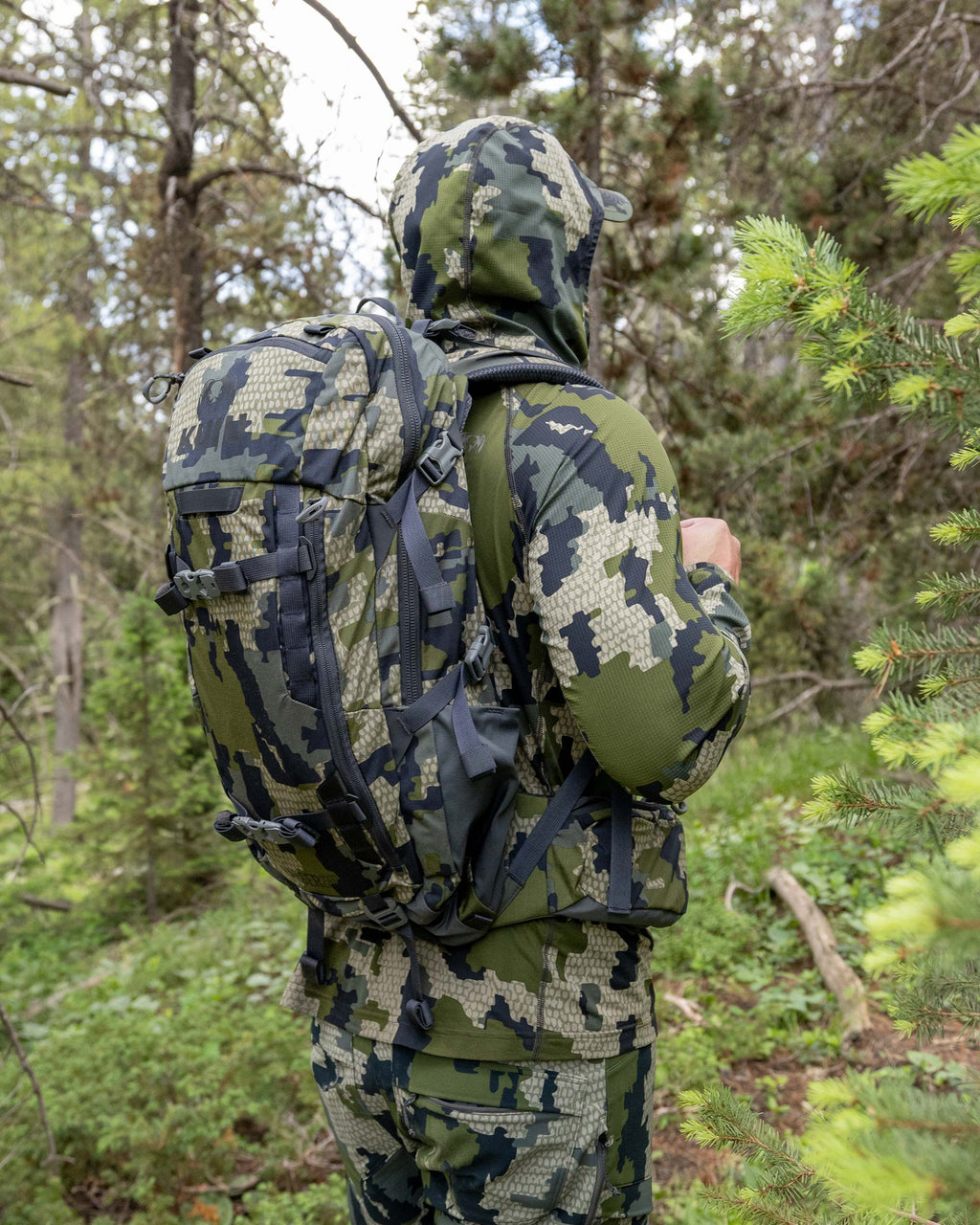 Side view of hunter standing in the middle of a green forest carrying the Ranger 2200 in Verde Camouflage