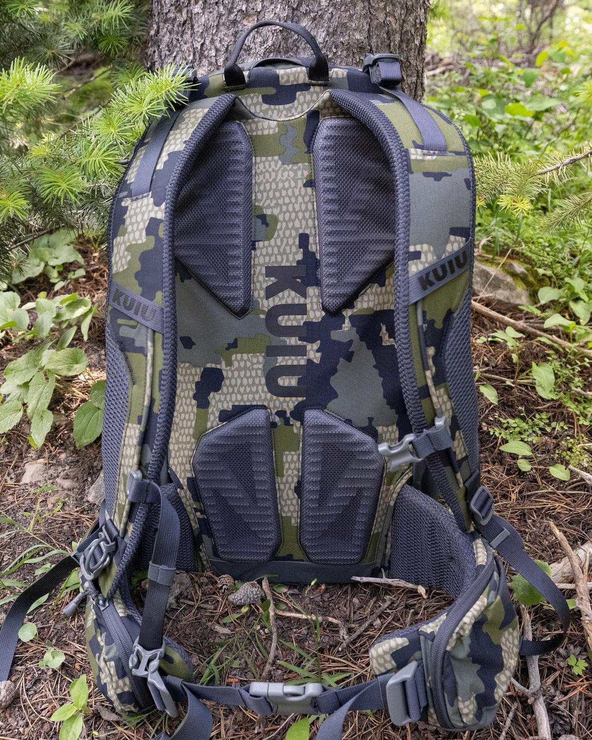 Back view of Ranger 2200 in Verde Camouflage on the ground leaning against a tree