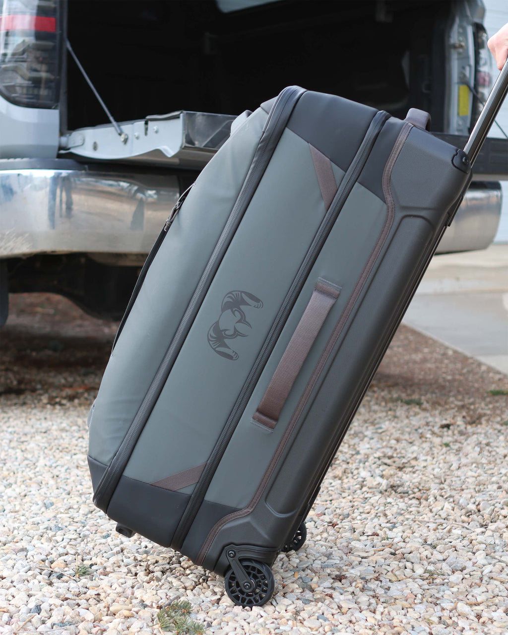 Side view of Waypoint 3000 Carry-On Roller in Gunmetal Grey over rough gravel