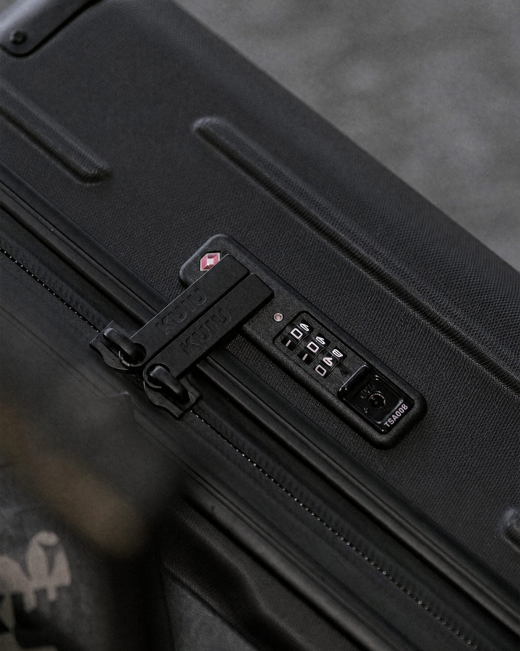 Close-up of a combination lock and zipper closure on a Hardline Spinner Carry-On in Black.