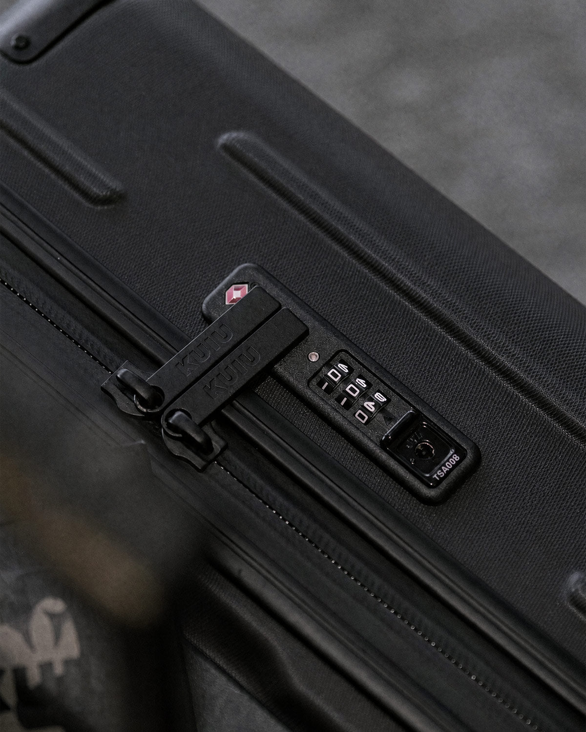 Close-up of a combination lock and zipper closure on a Hardline Spinner Carry-On in Black.