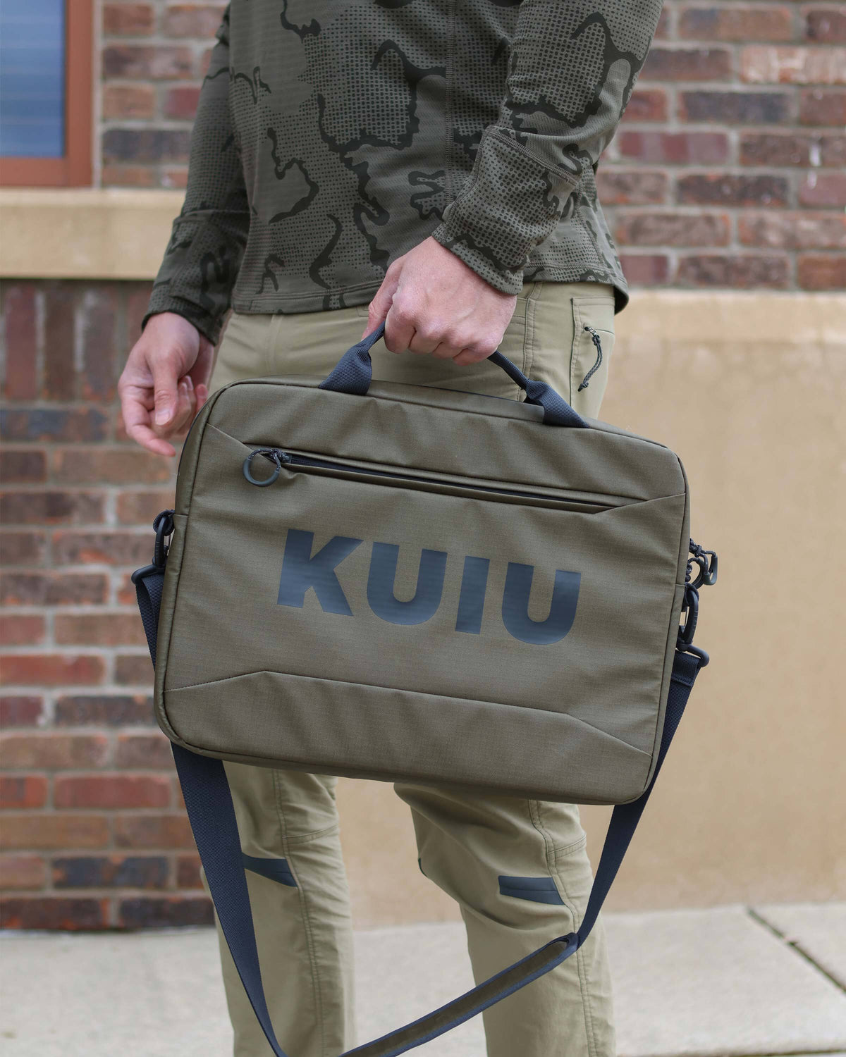 Man using grab handle to carry Waypoint Messenger Bag in Bourbon Brown