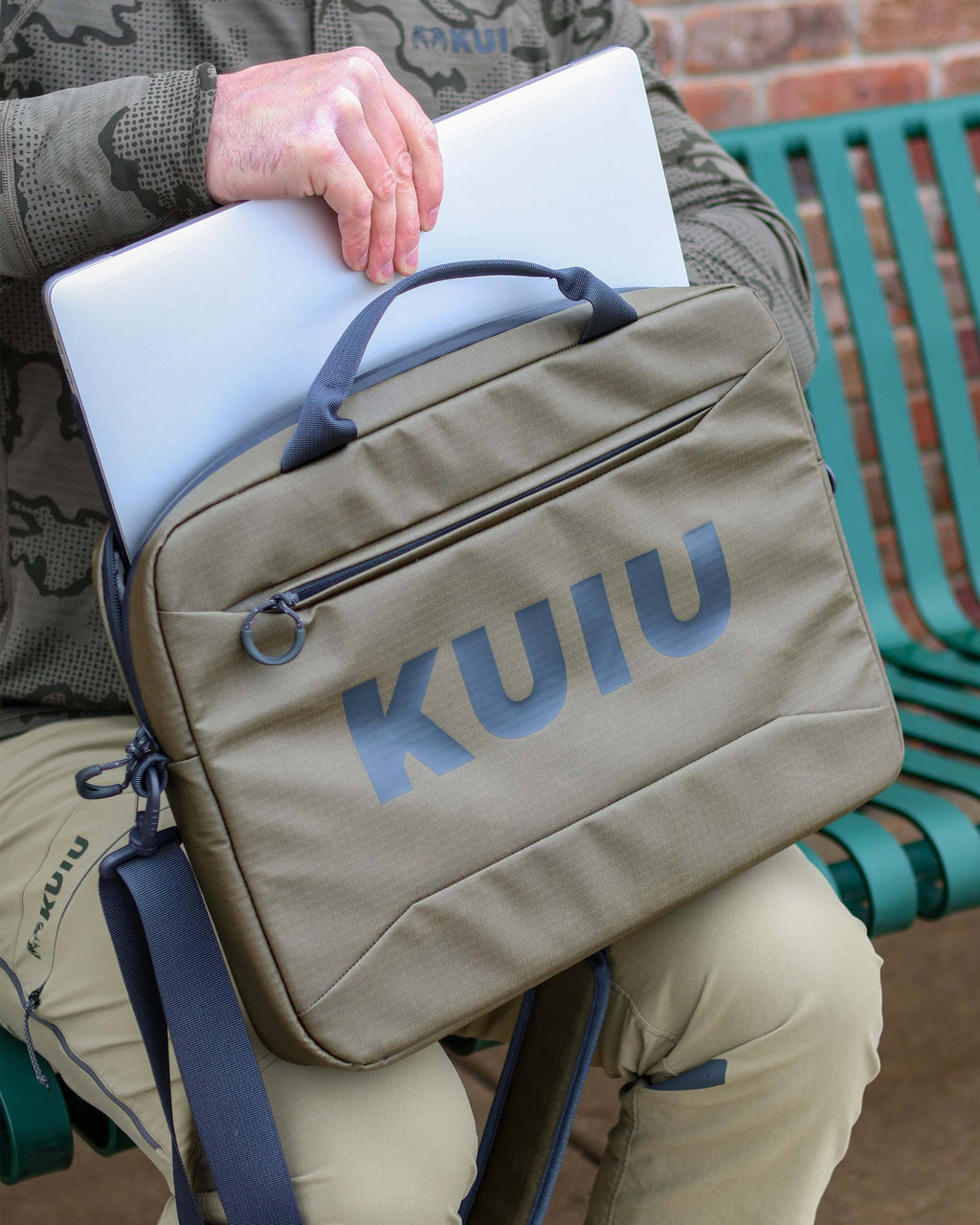 Close-up of man storing a laptop in the Waypoint Messenger Bag in Bourbon Brown