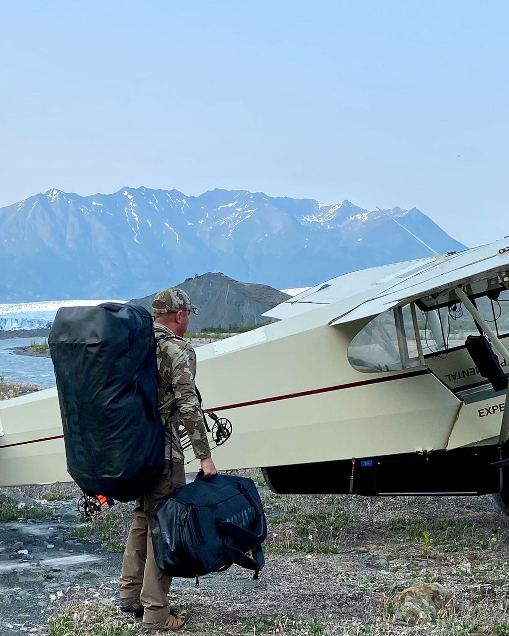 Picture of hunter wearing black Waypoint 10400 Duffel bag on back as he waits to board a small bush plane
