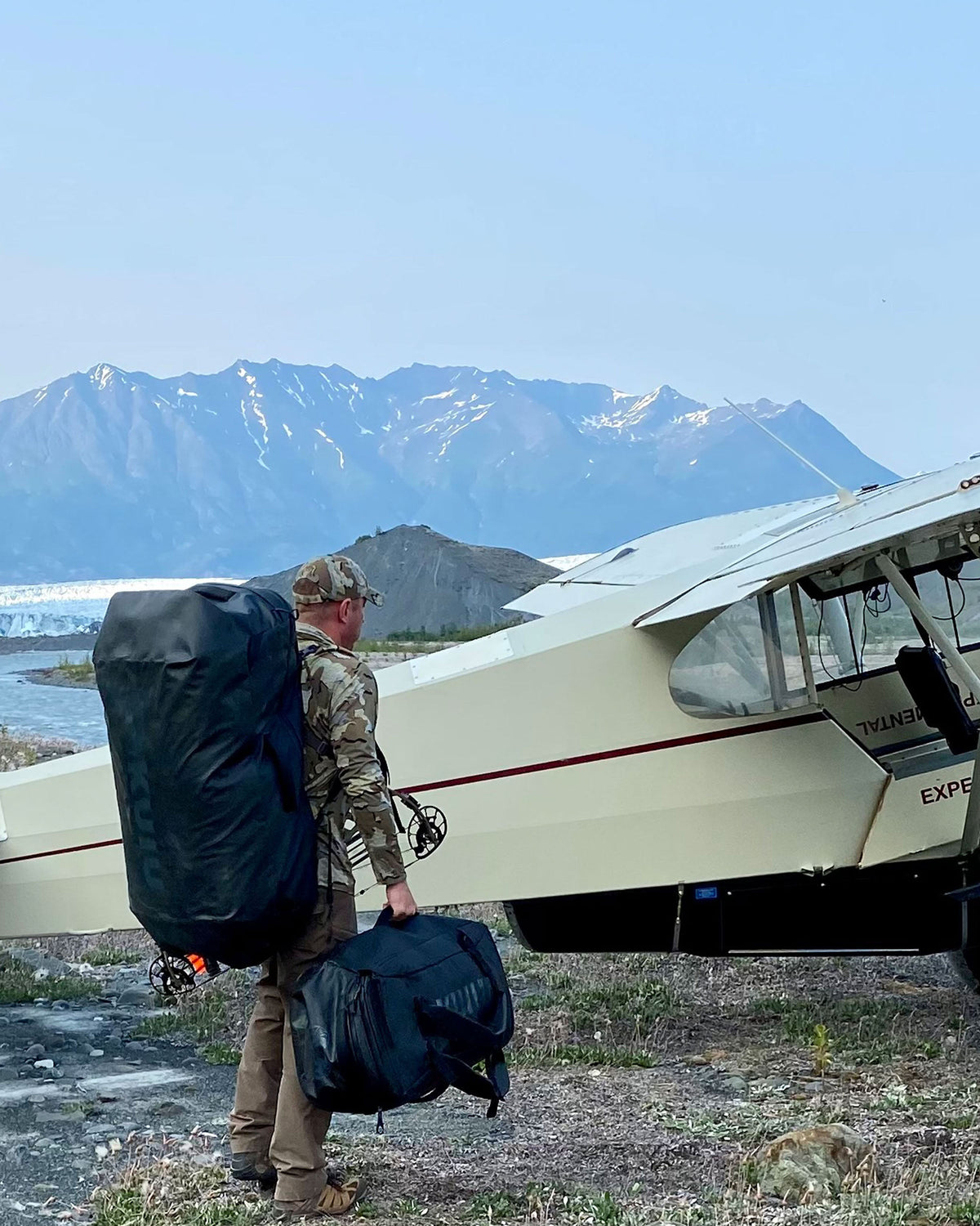 Picture of hunter wearing black Waypoint 10400 Duffel bag on back as he waits to board a small bush plane