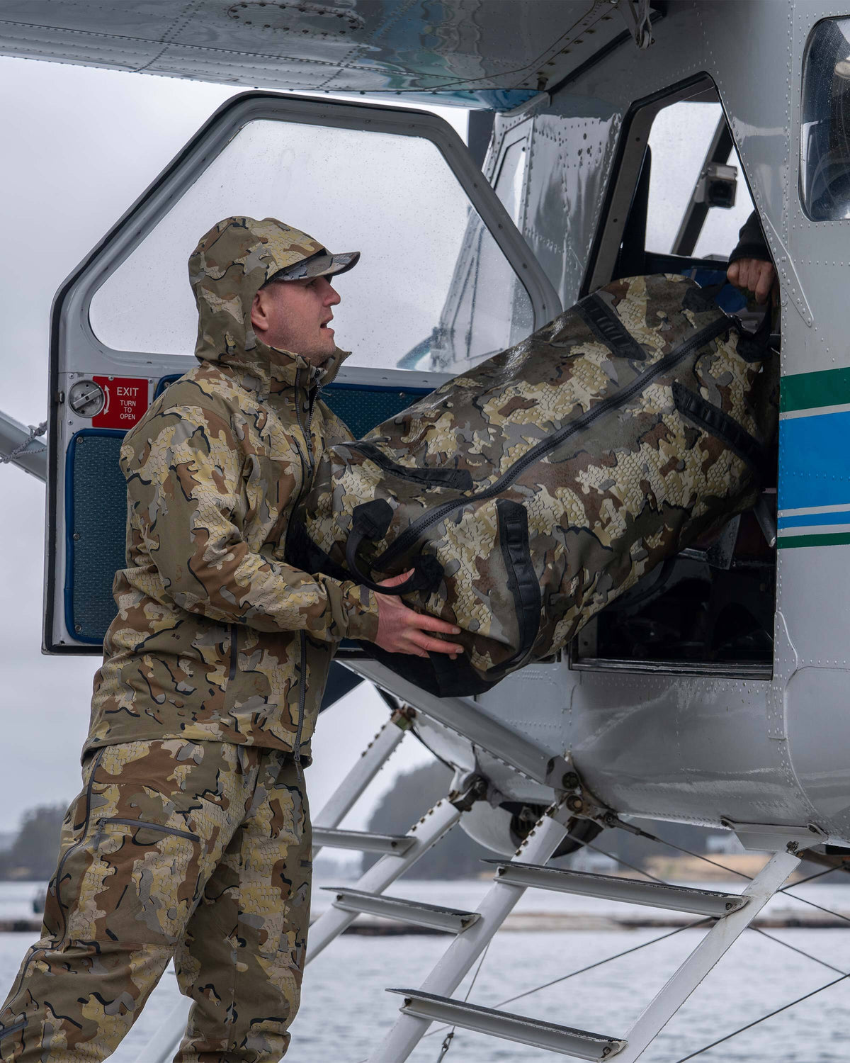 Hunter Loading Kodiak 6600 Submersible Duffel in Valo Camouflage onto Float Plane