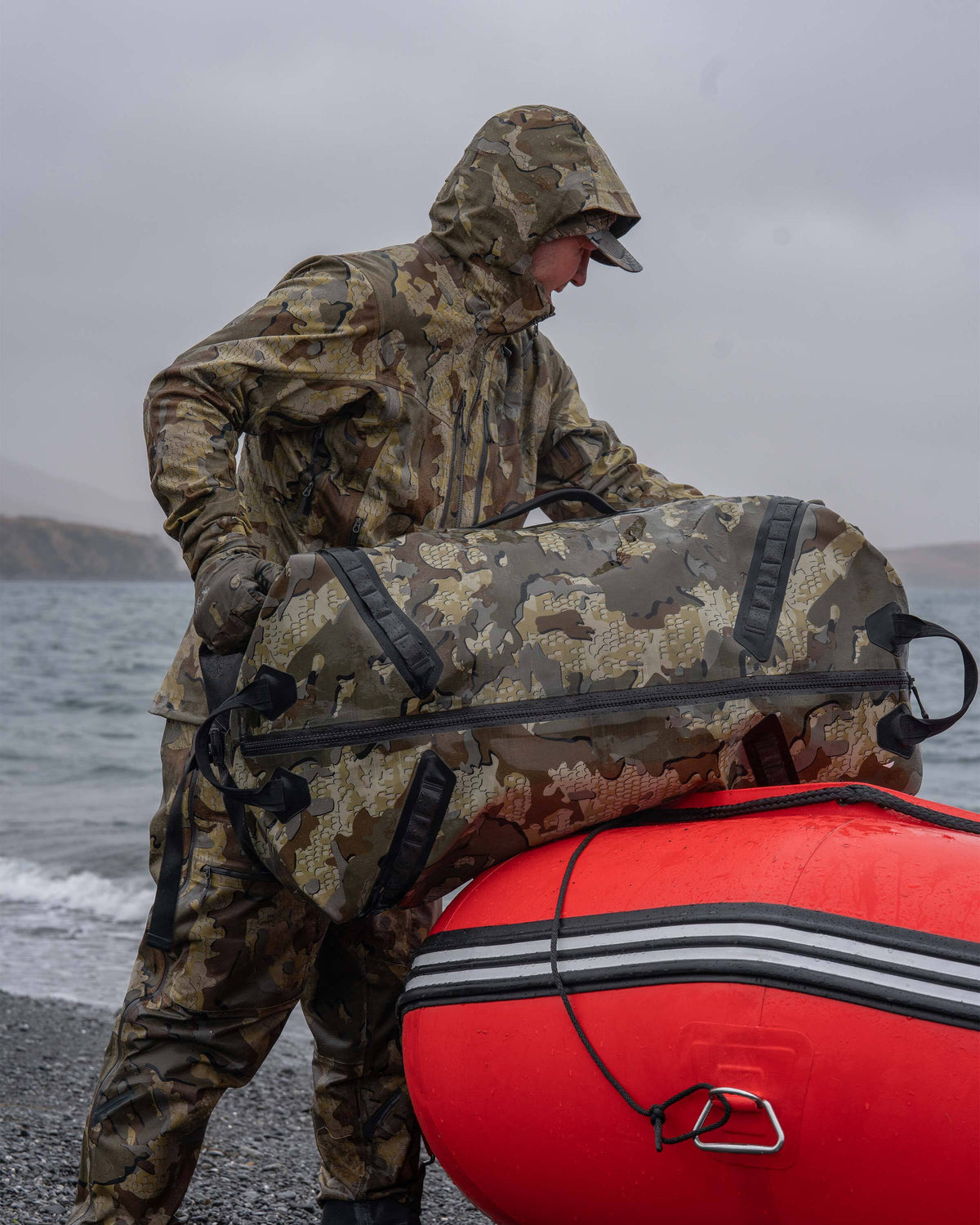 Hunter Resting Kodiak 6600 Submersible Duffle in Valo Camouflage on Orange Inflatable Raft