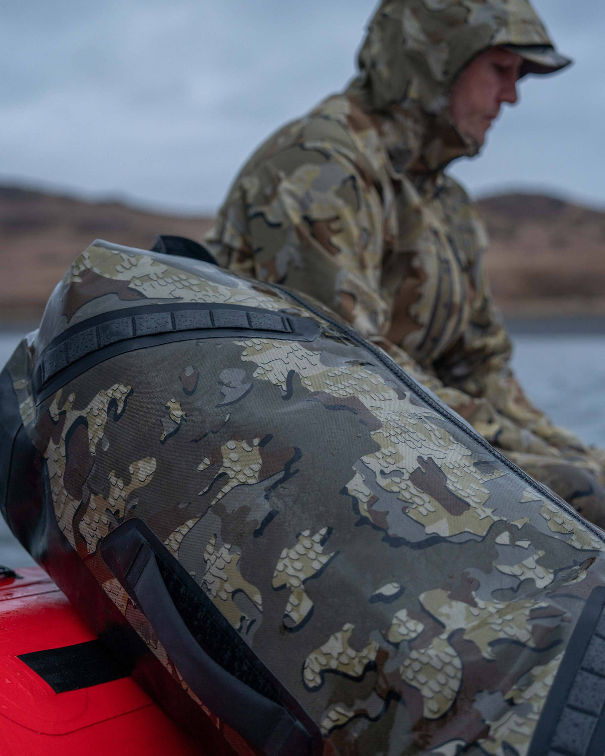 Kodiak 6600 Submersible Duffel in Valo Camouflage Resting on Raft with Hunter in the Background