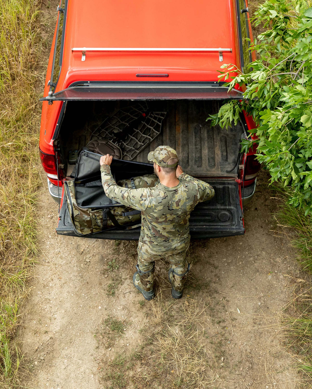 Birds eye view of Hunter unzipping the TwoTrack 8000 Boot Duffel in Valo Camouflage on the back of this truck tailgates