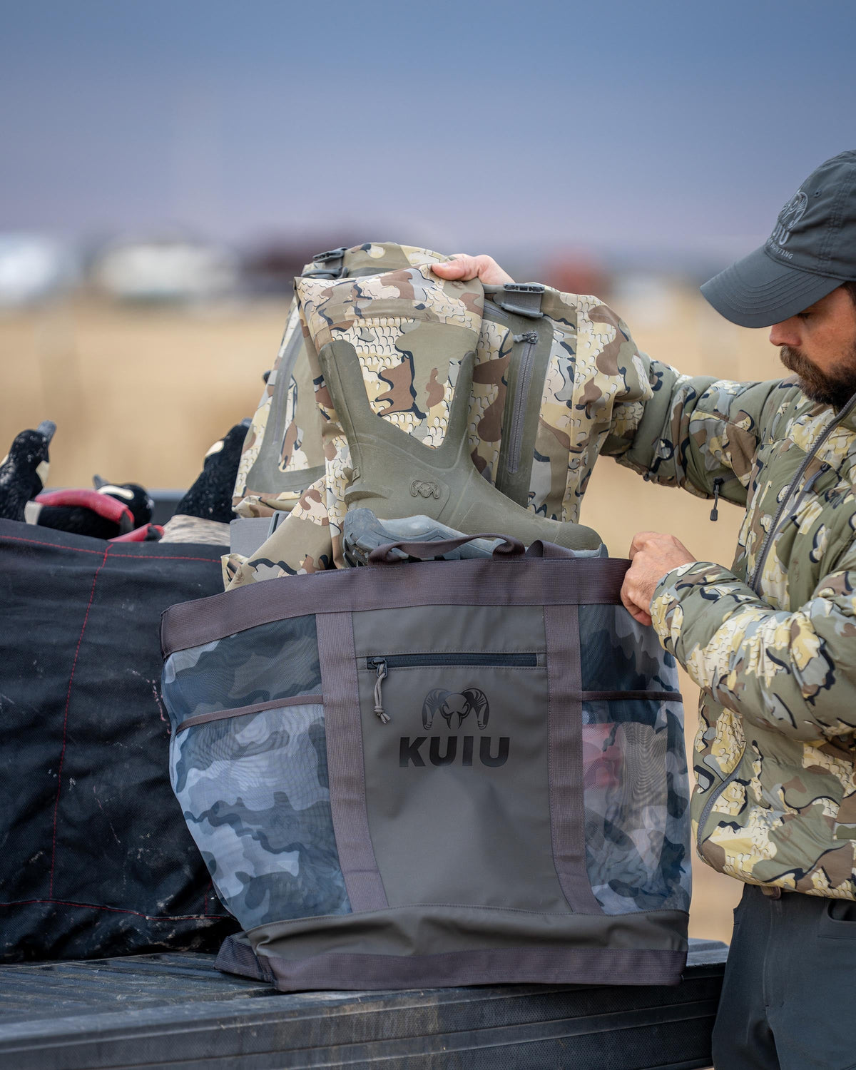 Hunter pulls out KUIU HD Mud Boots and KUIU HD Flex Wader in Valo Camouflage from KUIU 3500 Mesh Tote Bag in Vias Storm