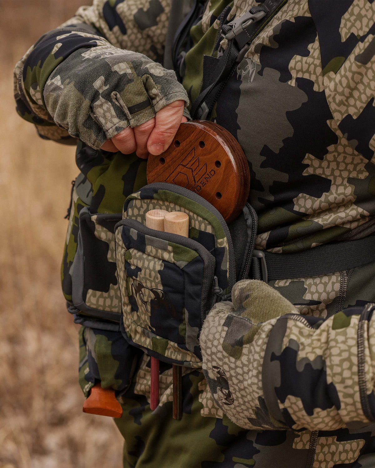 Hunter stowing slate pot call with striker in the Slate Call Holder in Verde Camouflage