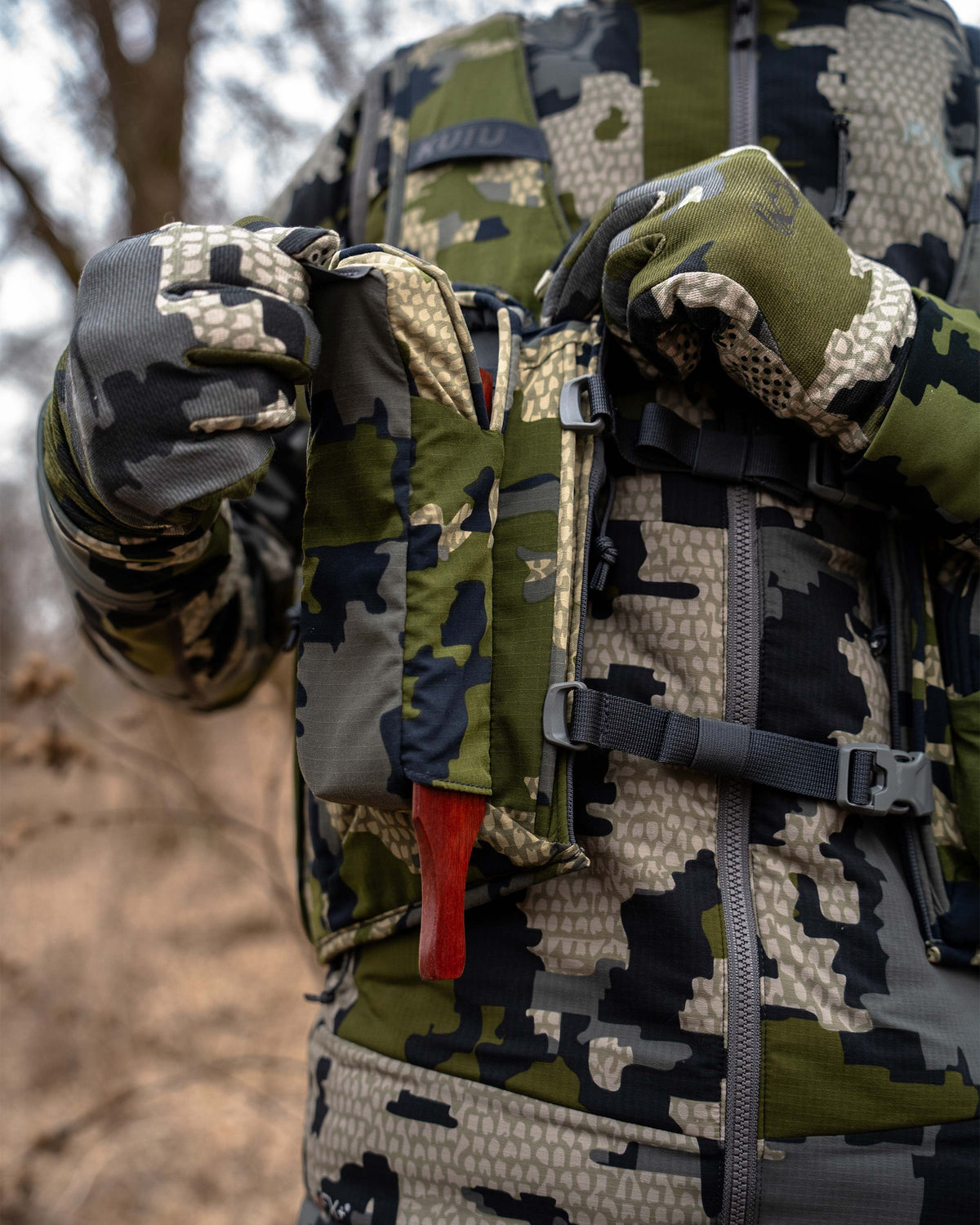 Front view of box call holder with magnetic closure pocket, displaying box call securely stored inside on the KUIU Rival Turkey Vest in Verde Camouflage