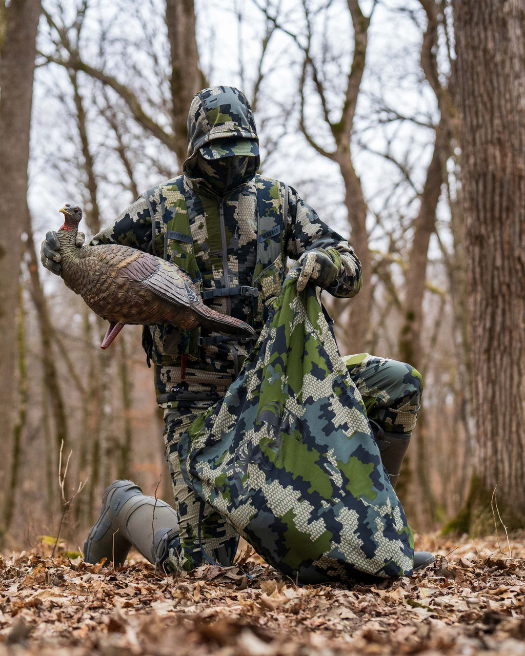 Hunter stowing a decoy turkey in the turkey carry bag in Verde Camouflage