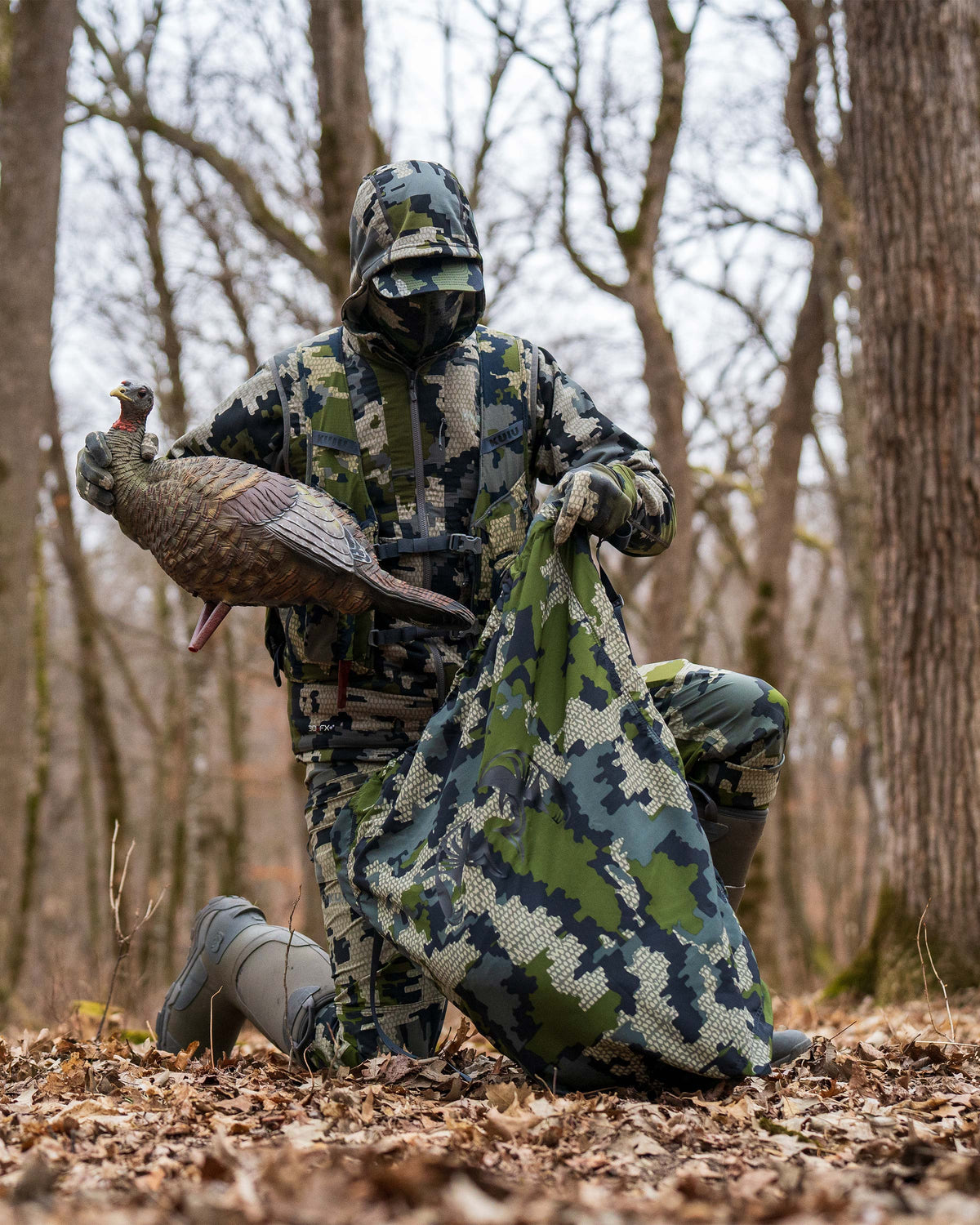 Hunter stowing a decoy turkey in the turkey carry bag in Verde Camouflage