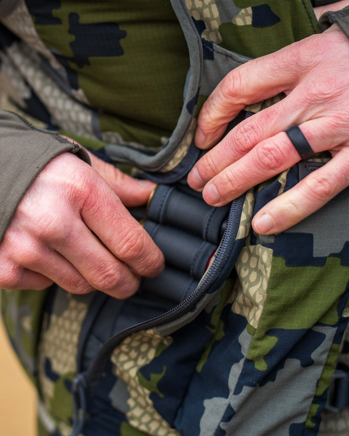 Close view of Hunter removing a shell holder from the side zippered pocket on the Rival Turkey Vest in Verde Camouflage