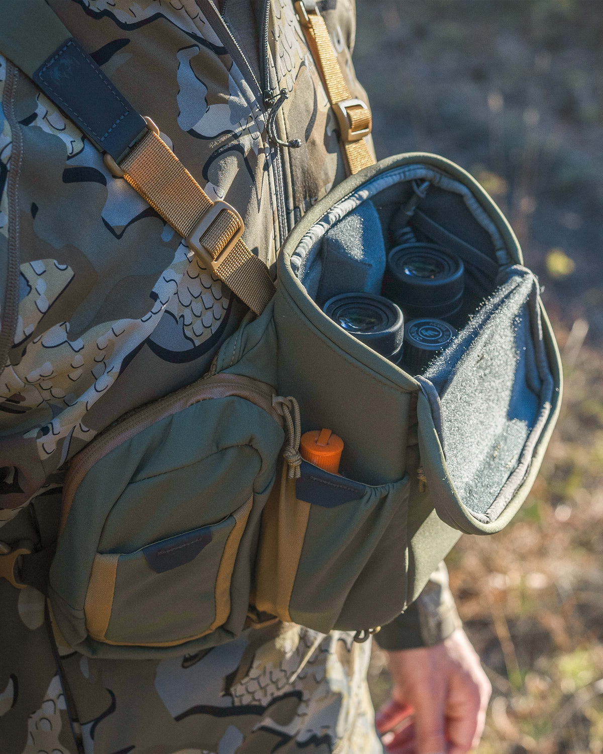 Hunter wearing the PRO Chest Pack in Evergreen, Highlighting overlapped forward-folding lid and a binocular nestled inside the main compartment
