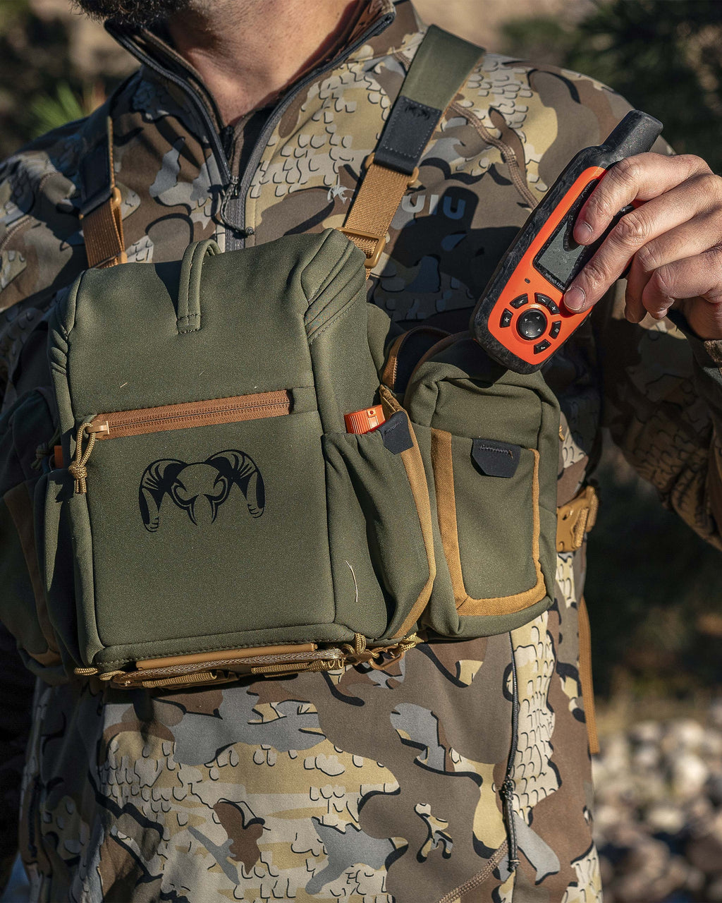 Hunter stowing an accessory item in the zip-closure side pockets on the PRO Chest Pack in Evergreen