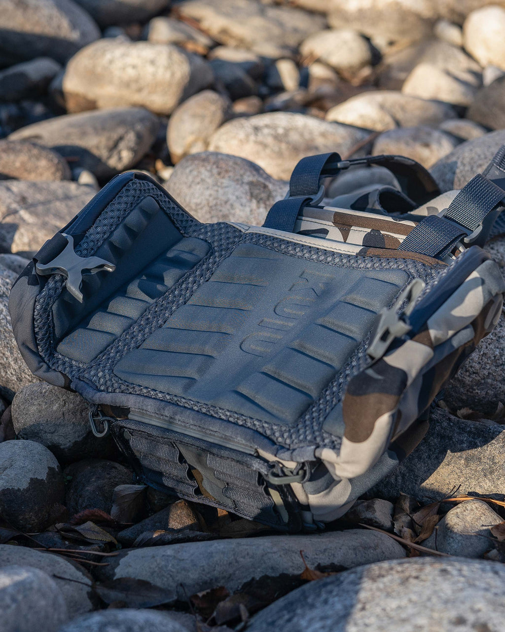 PRO Chest Pack in Vias Camouflage placed on top of rocks, Highlighting ergonomic and highly breathable molded foam back panel