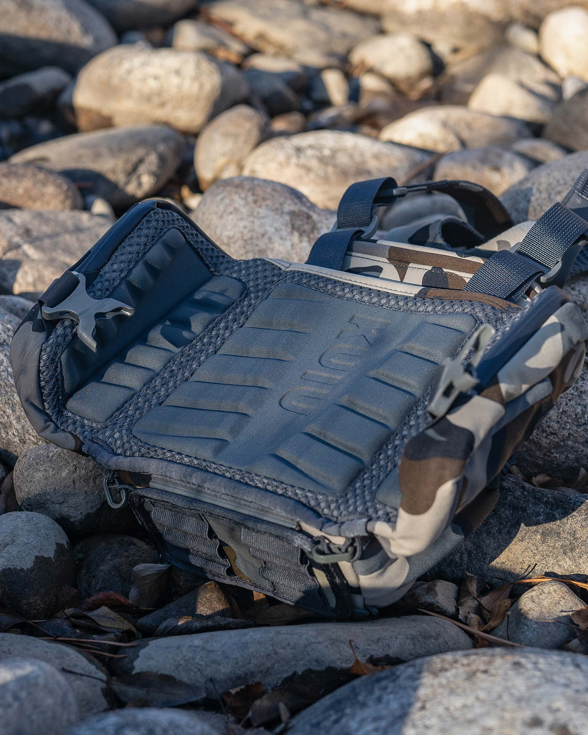 PRO Chest Pack in Vias Camouflage placed on top of rocks, Highlighting ergonomic and highly breathable molded foam back panel