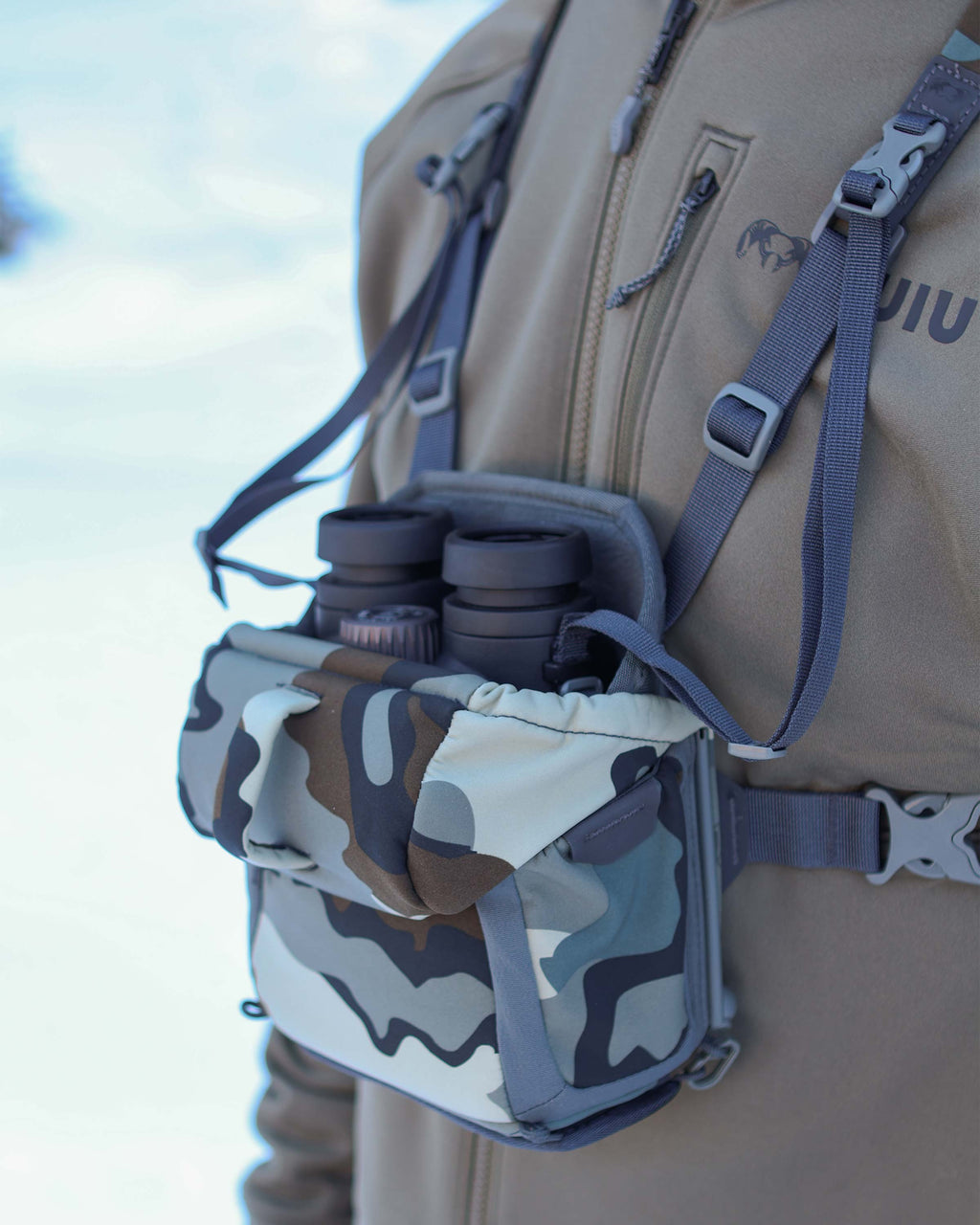 Angled view of Binocular nestled inside the main compartment of the PRO G3 Bino Harness in Vias Camouflage, Highlighting overlapped forward-folding lid