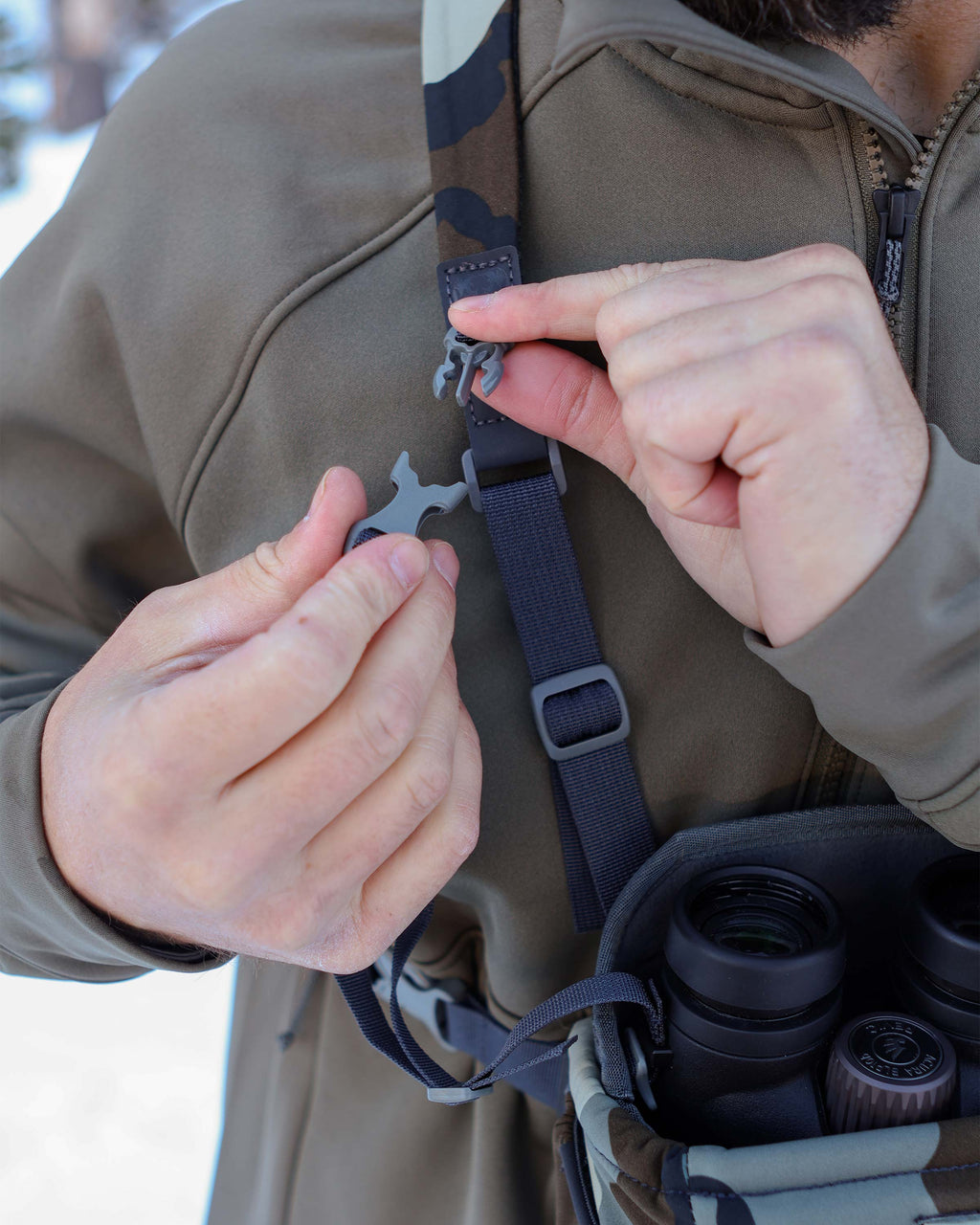 Hunter connecting the main pouch internal strap with the front strap connector on the PRO G3 Bino Harness in Vias Camouflage