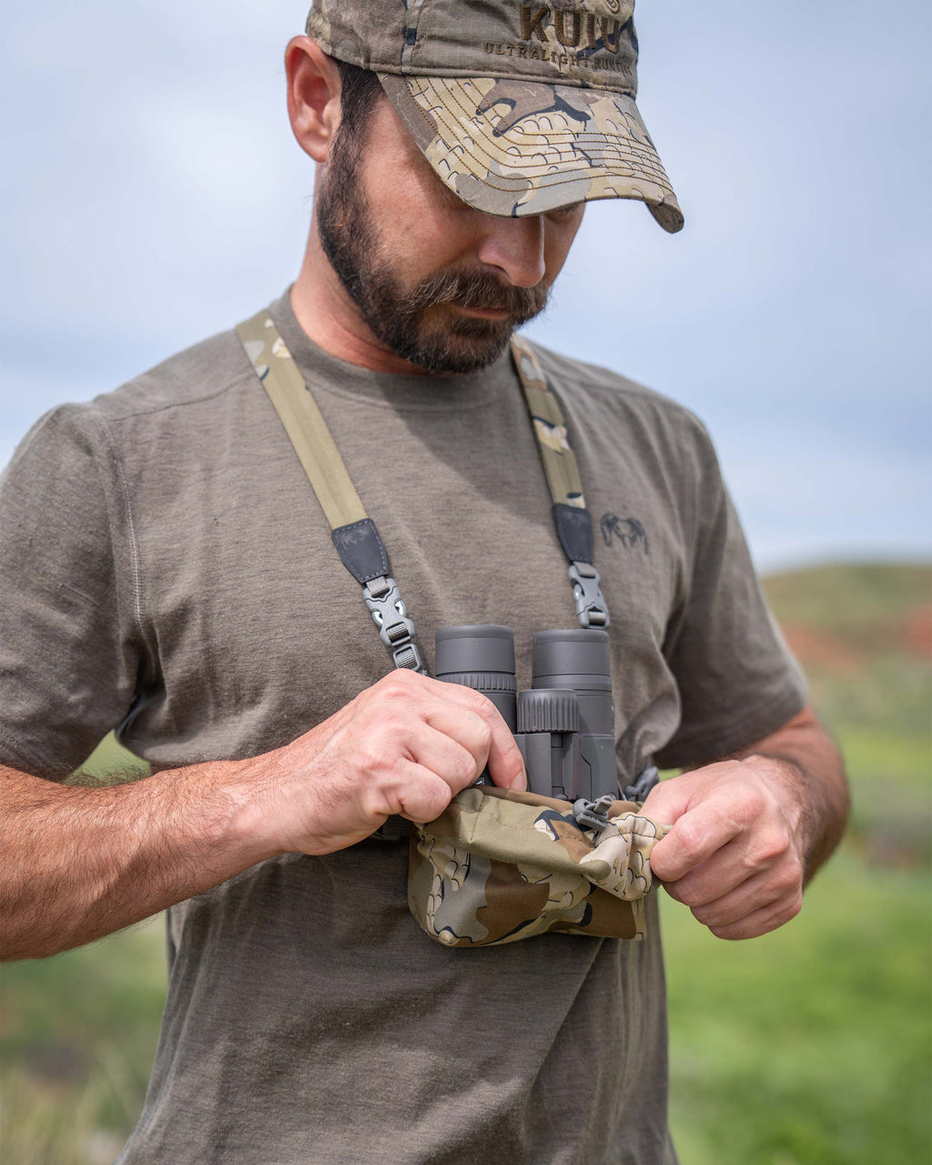Hunter removing his binocular from front pouch of the Ultralight Bino Harness in Valo Camouflage