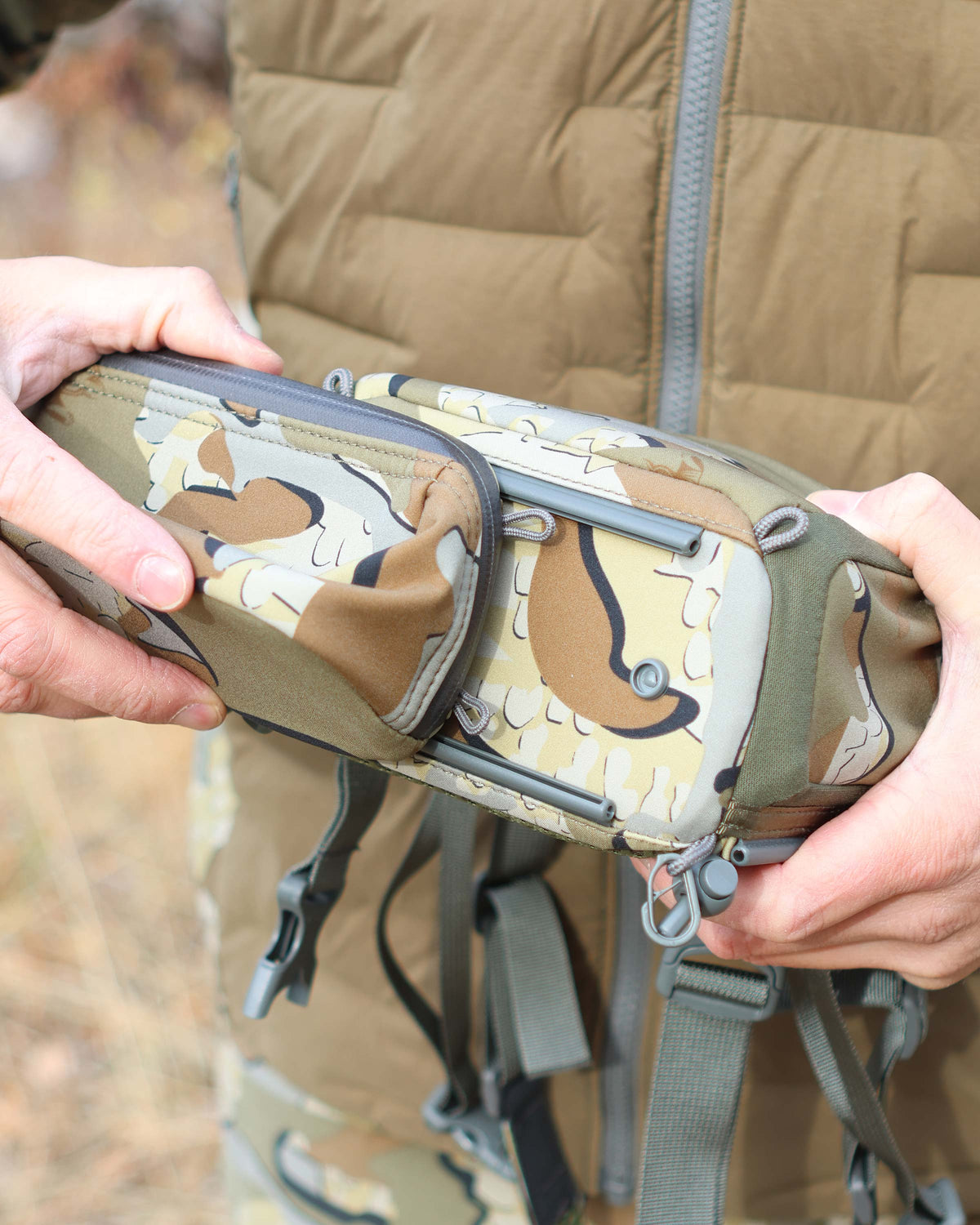 Bottom view of PRO G3 Bino Harness Accessory Pocket being attached to the PRO G3 Bino Harness in Valo Camouflage, Highlighting rail-lock connection system
