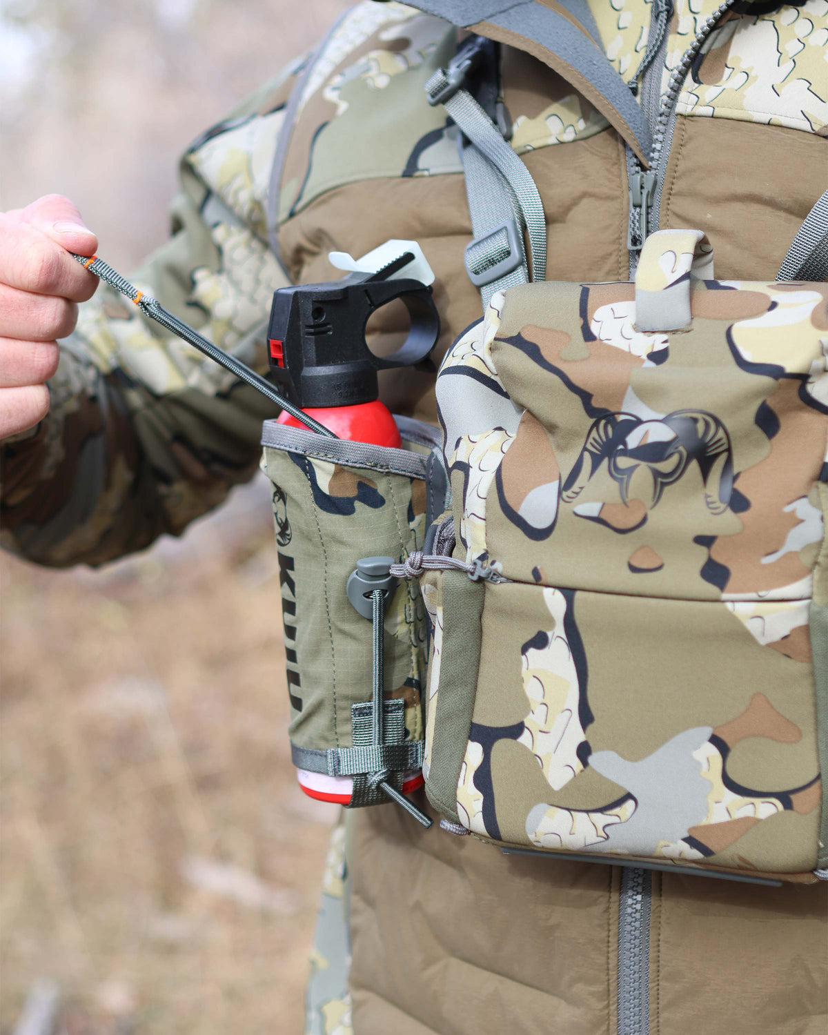 Front of Hunter wearing PRO Bino Harness with PRO G3 Bear Spray Holder in Valo Camouflage, Highlighting adjustable pull tab and cord