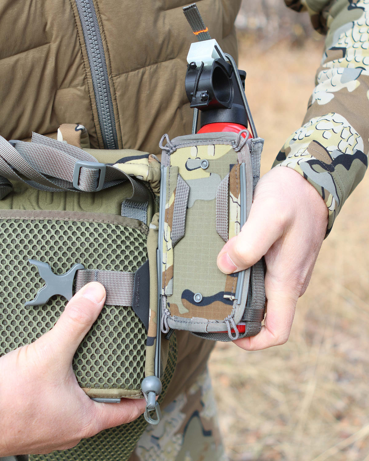 Close-up of Hunter using the rail-lock connection to attach the PRO G3 Bear Spray Holder in Valo Camouflage on the PRO G3 Bino Harness in Valo Camouflage
