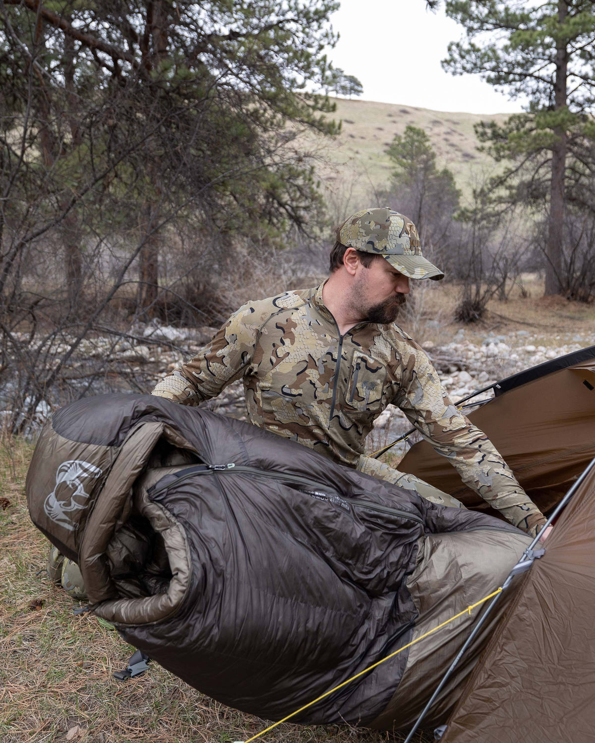 Hunter sliding his Super Down Altai 0 degree sleeping bag in Ash Brown into his Mountain Star 3 Person Tent in preparation for sleep