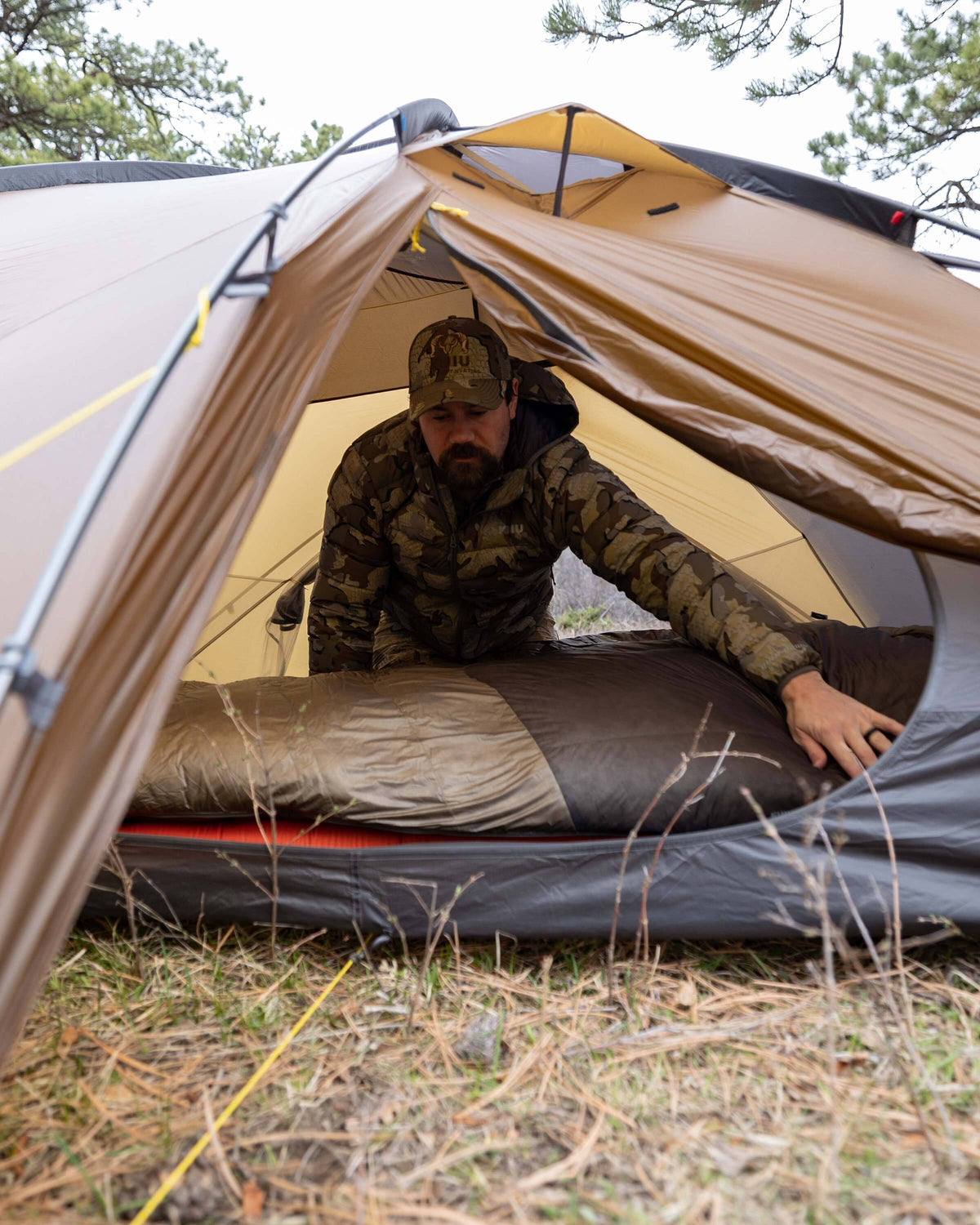 Hunter laying out his Super Down Altai 0 degree sleeping bag in Ash Brown inside of his Mountain Star 3 Person Tent in preparation for sleep