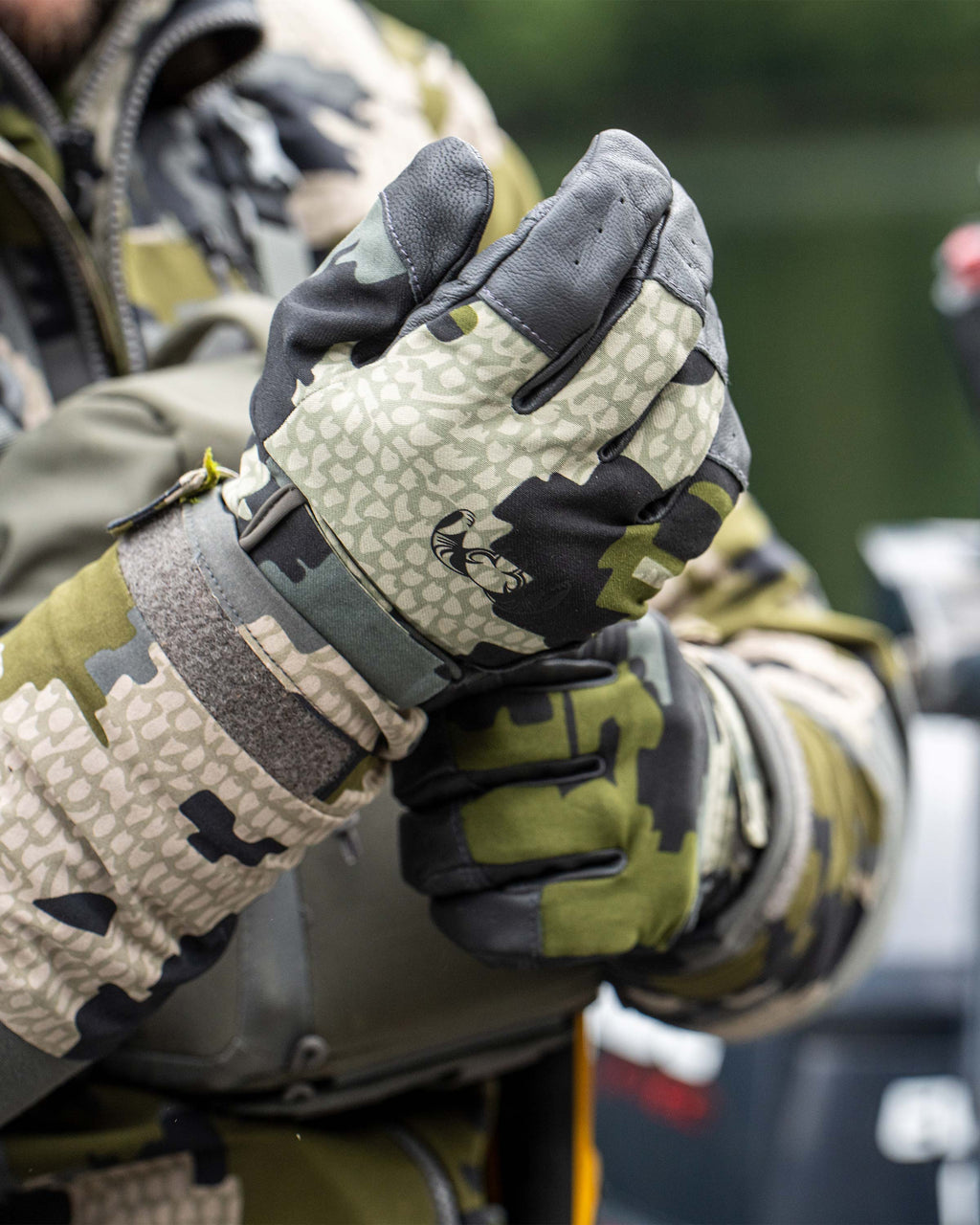 Close-up of hunter adjusting Precision Glove in Verde Camouflage, Displaying articulated design, Featuring goat skin leather across the grip, breathable and quick-dry material on back of hand, seamless finger patterning at touch points,  and perforated vents across the palm and fingers