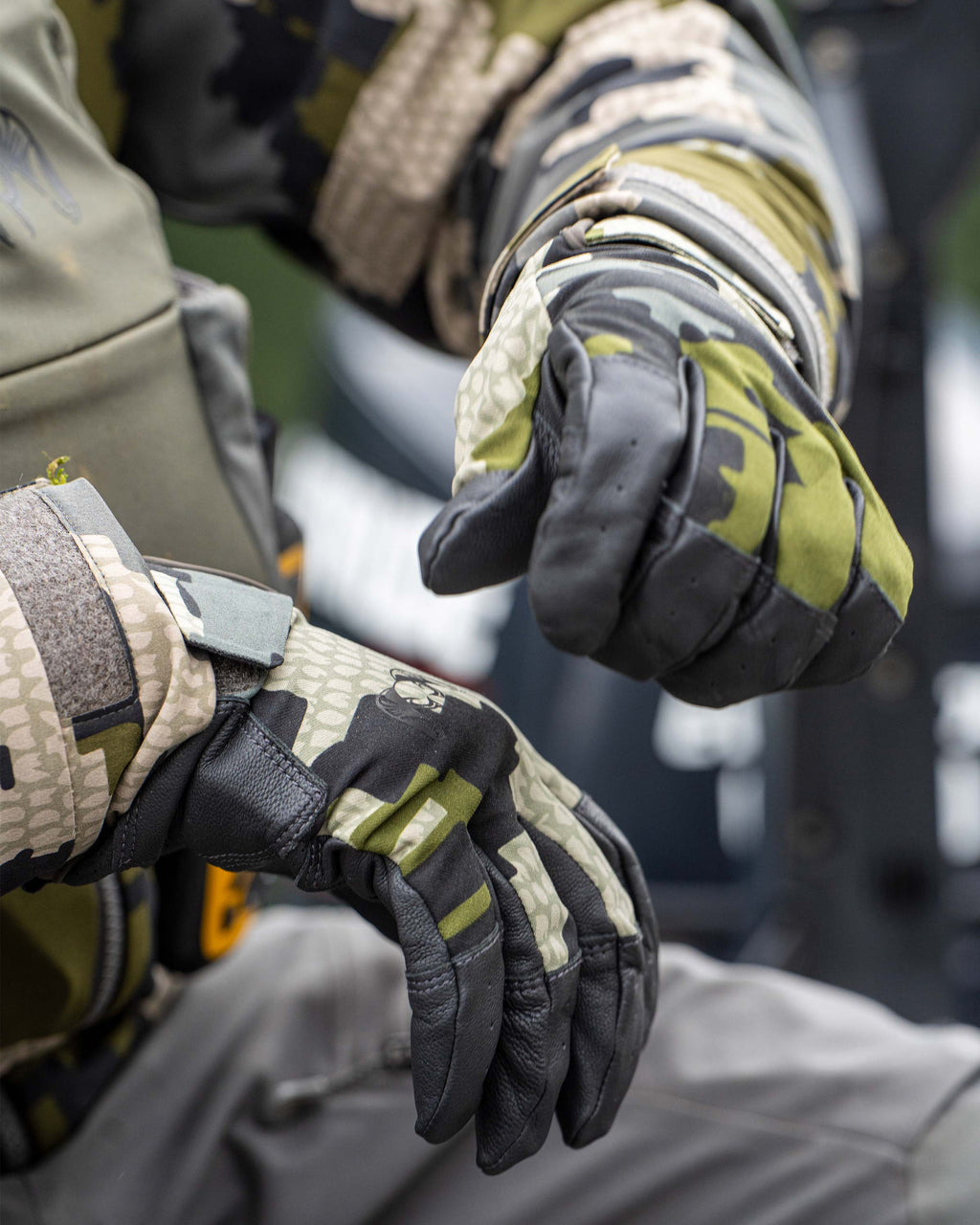 Close-up of hunter adjusting Precision Glove in Verde Camouflage, Displaying articulated design, Featuring goat skin leather across the grip, breathable and quick-dry material on back of hand, seamless finger patterning at touch points, and perforated vents across the palm and fingers