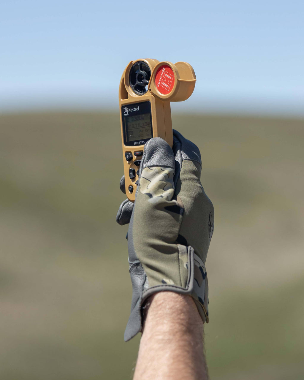Hunter holding up wind meter wearing Precision Glove in Valo Camouflage